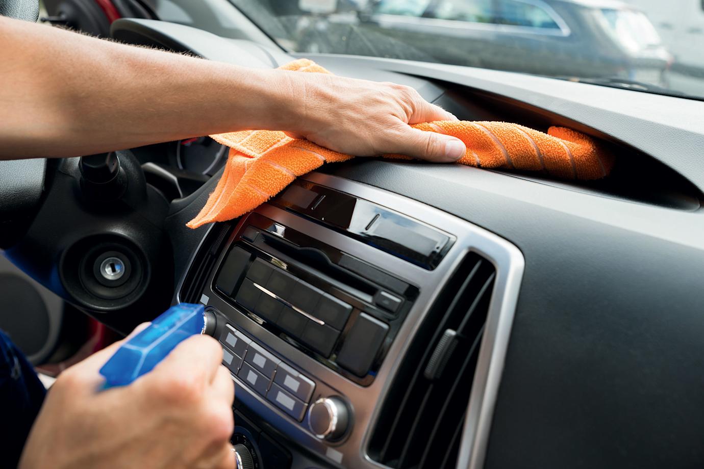 A driver cleans their car dashboard.
