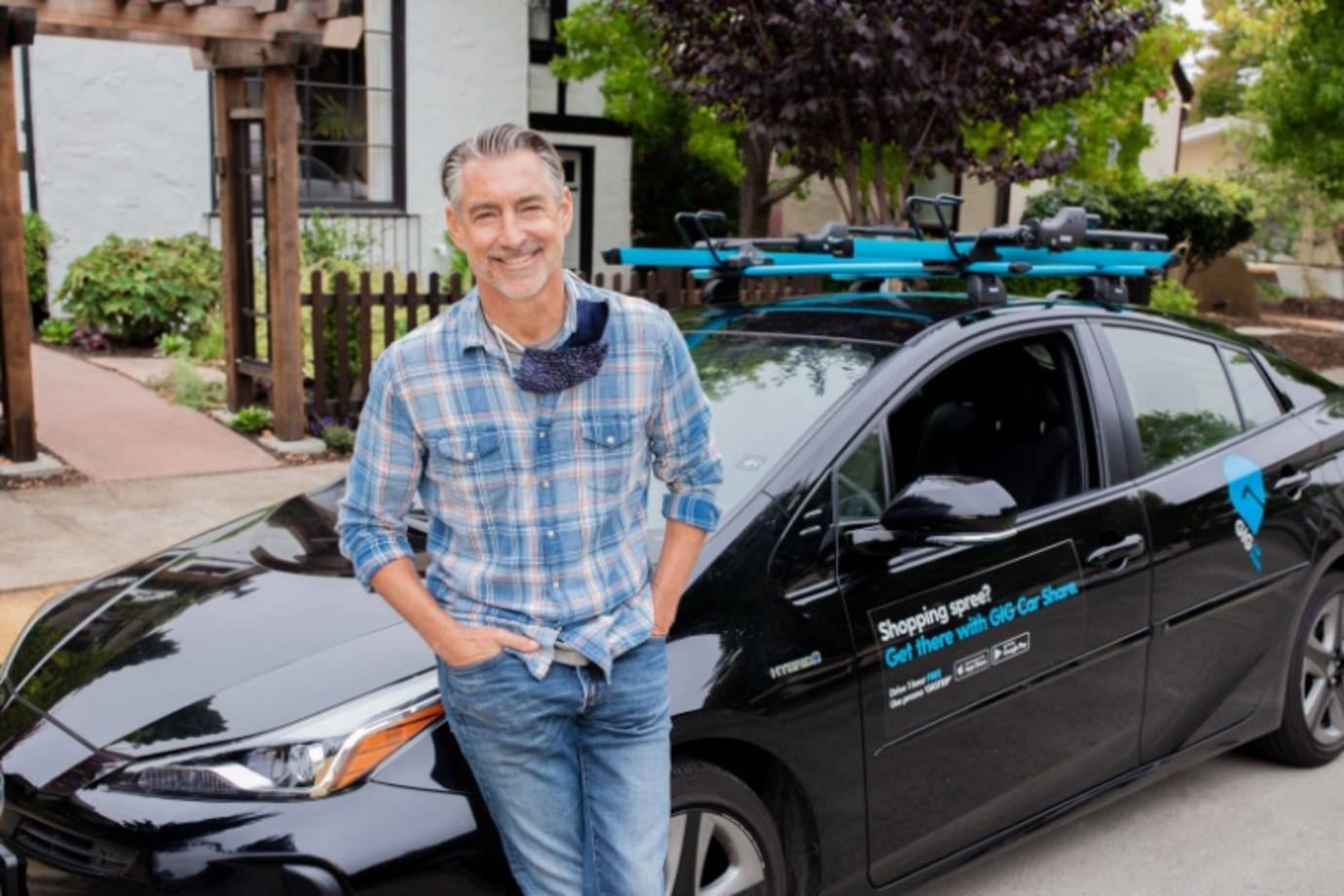 A man stands next to a GIG car powered by AAA
