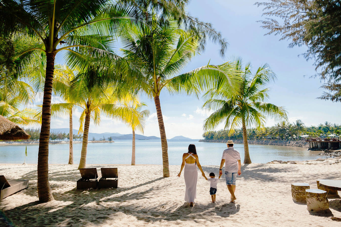 A family walks on the beach together at a luxury tropical resort.