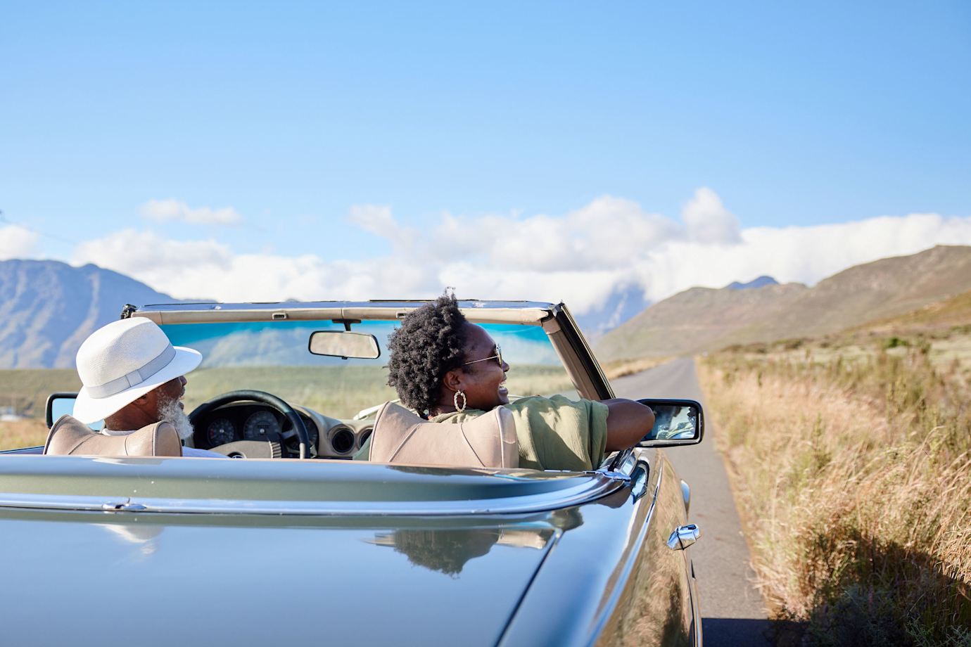 A couple drive in a vintage convertible.