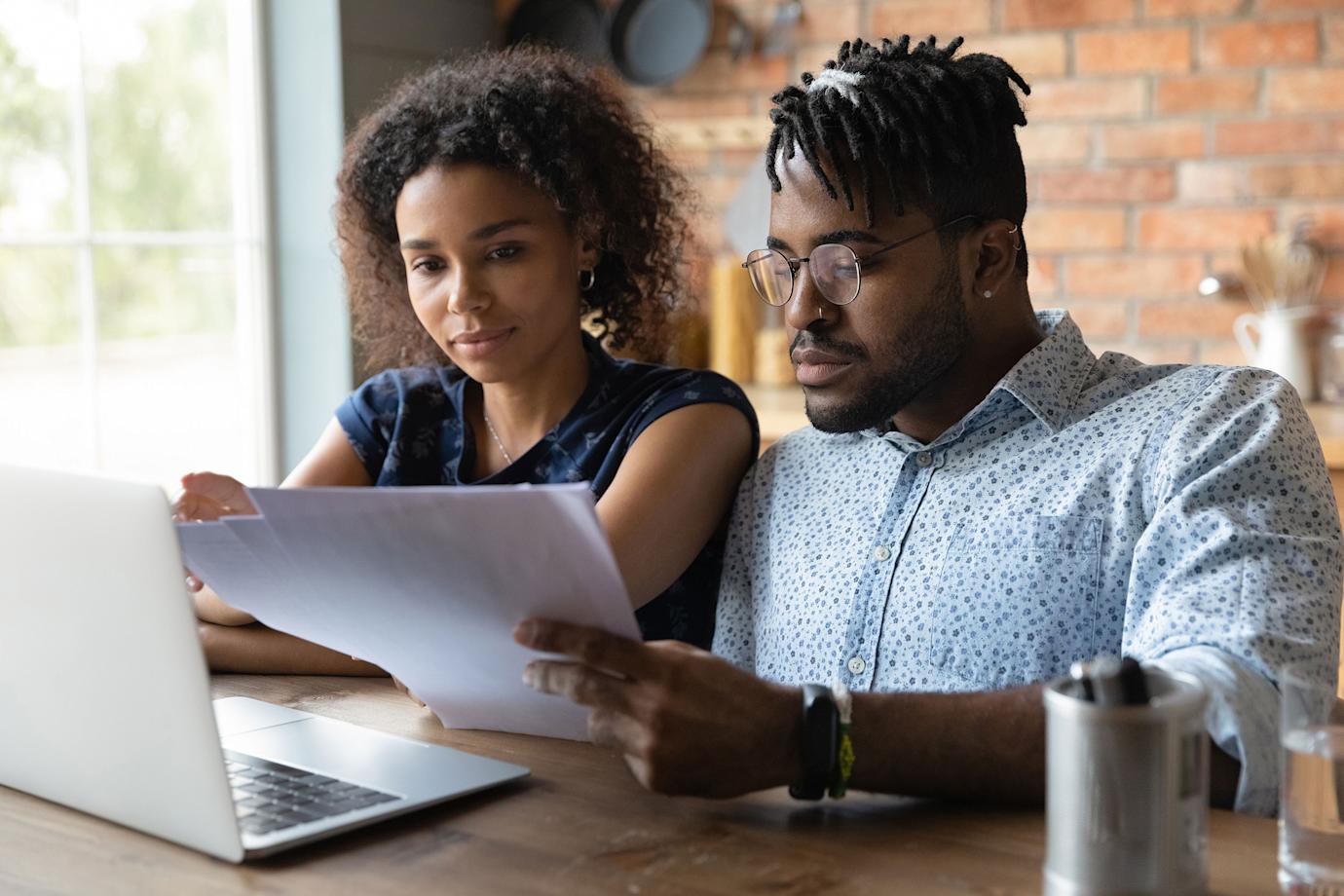 a couple go over the finances together at the kitchen table.