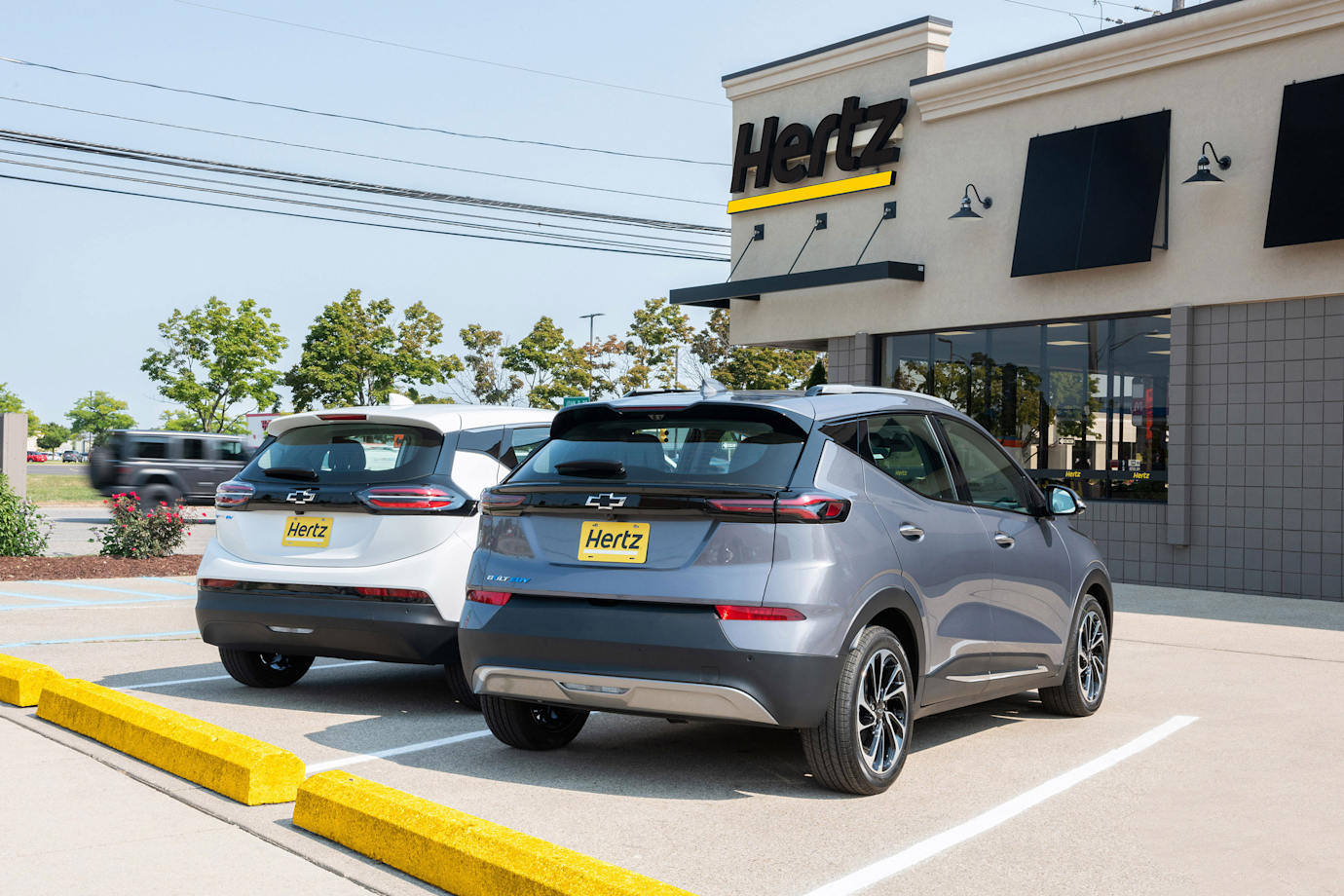 Chevy Bolts parked in a lot outside of a Hertz Rental Car agency in California.