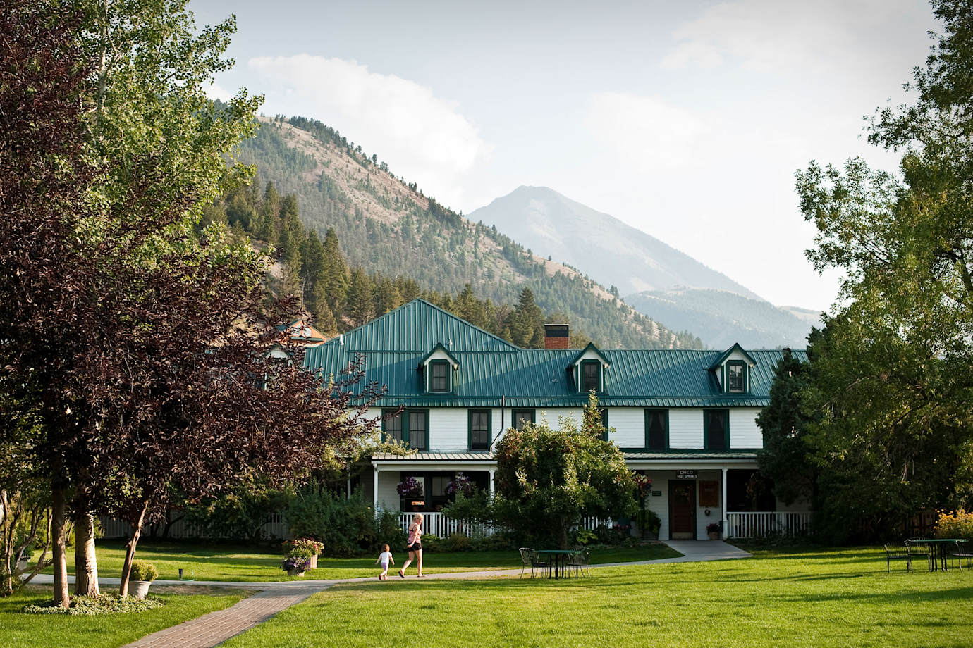 A mother and child walk outside at Chico Hot Springs in Pray, Montana with the mountains in the background.