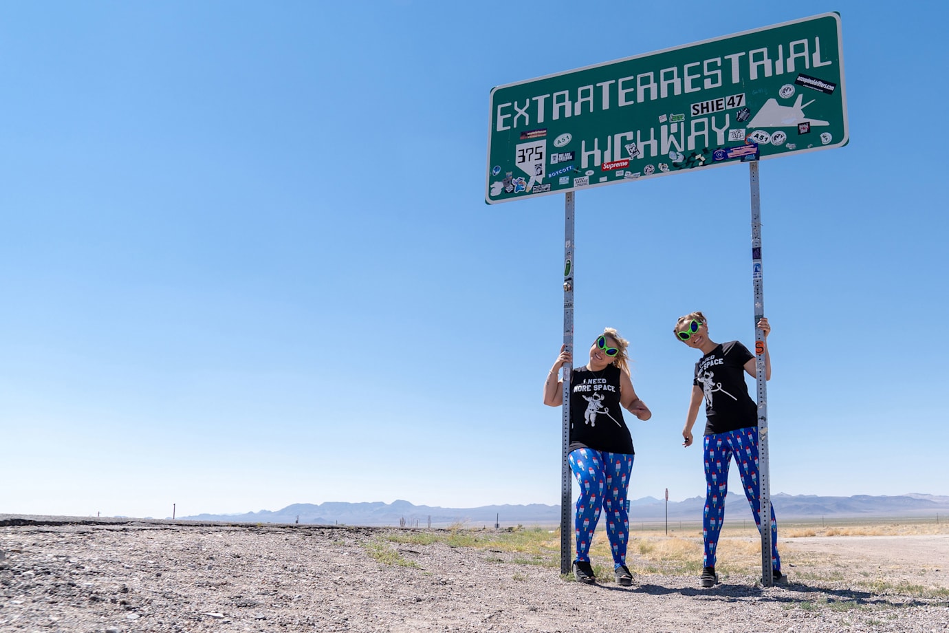 Two road-trippers pose under the Extraterrestrial Highway sign in Nevada.