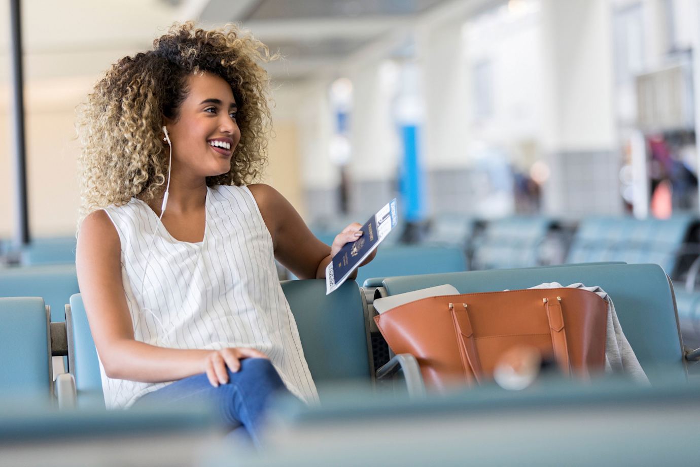A woman talks on the phone at the airport gate while waiting for her flight.