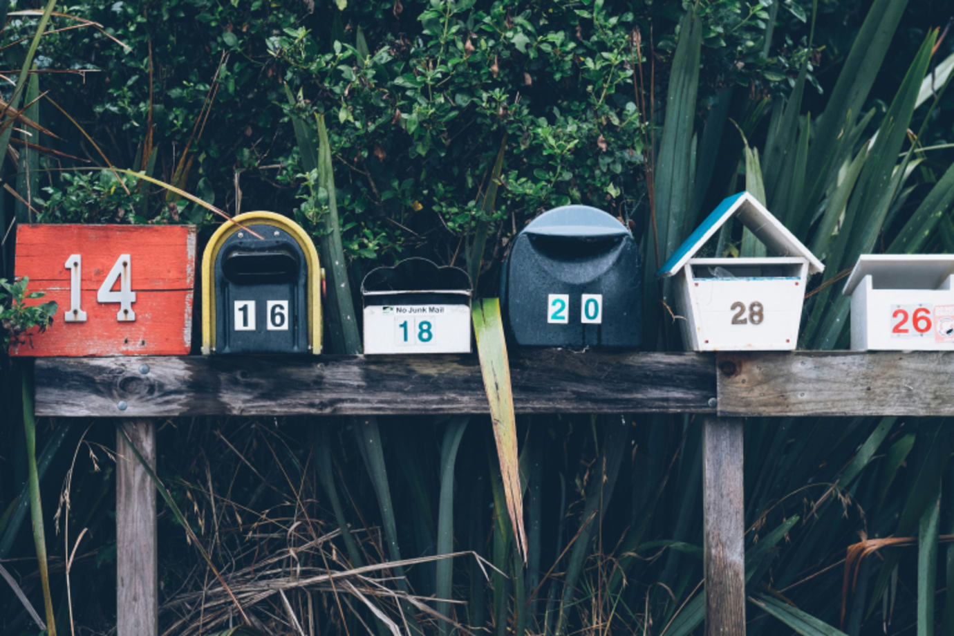 A row of mailboxes are lined up on a wooden post