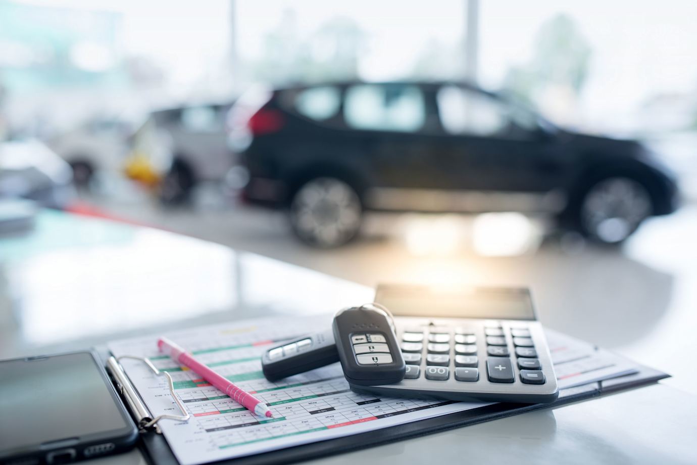 A calculator and two car key remotes placed on a table in a new car dealership.