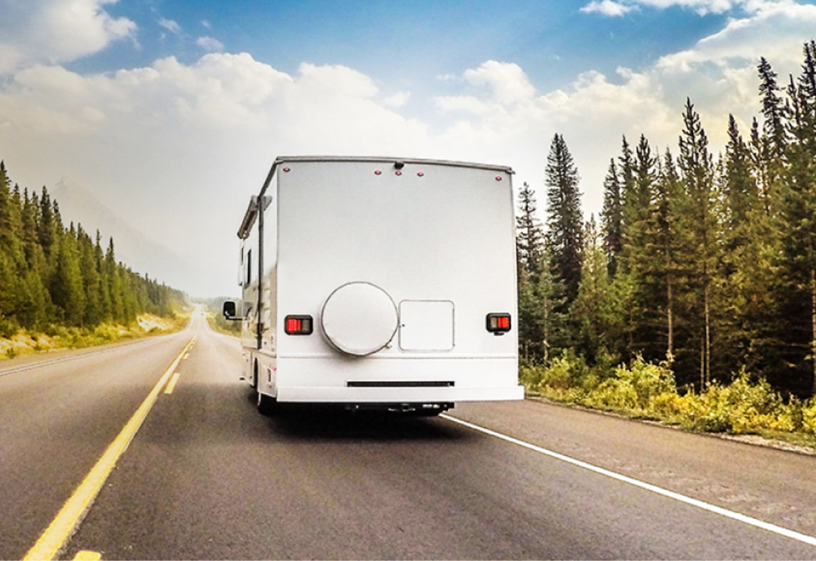 an insured RV drives down the road in a forested area