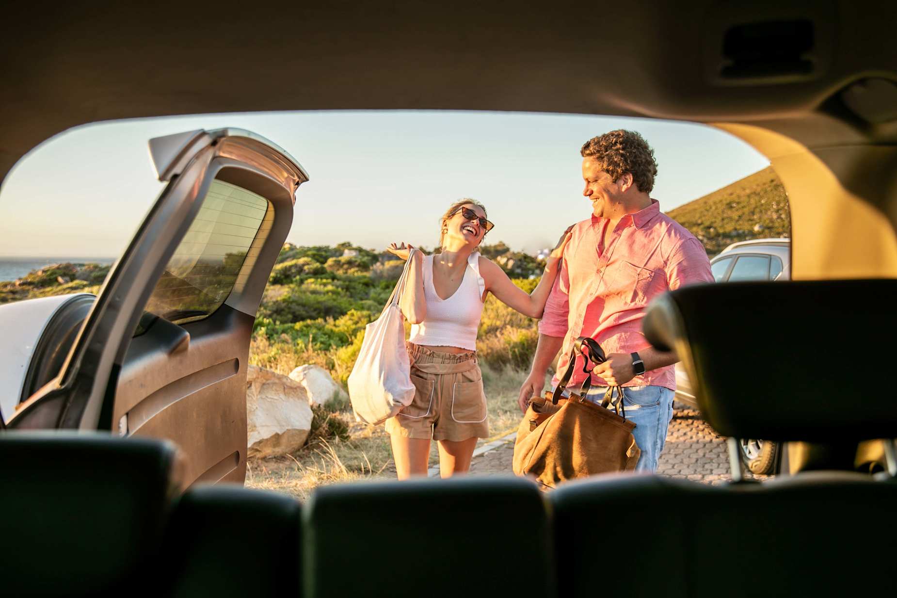 Man and woman sitting on car and watching sunset