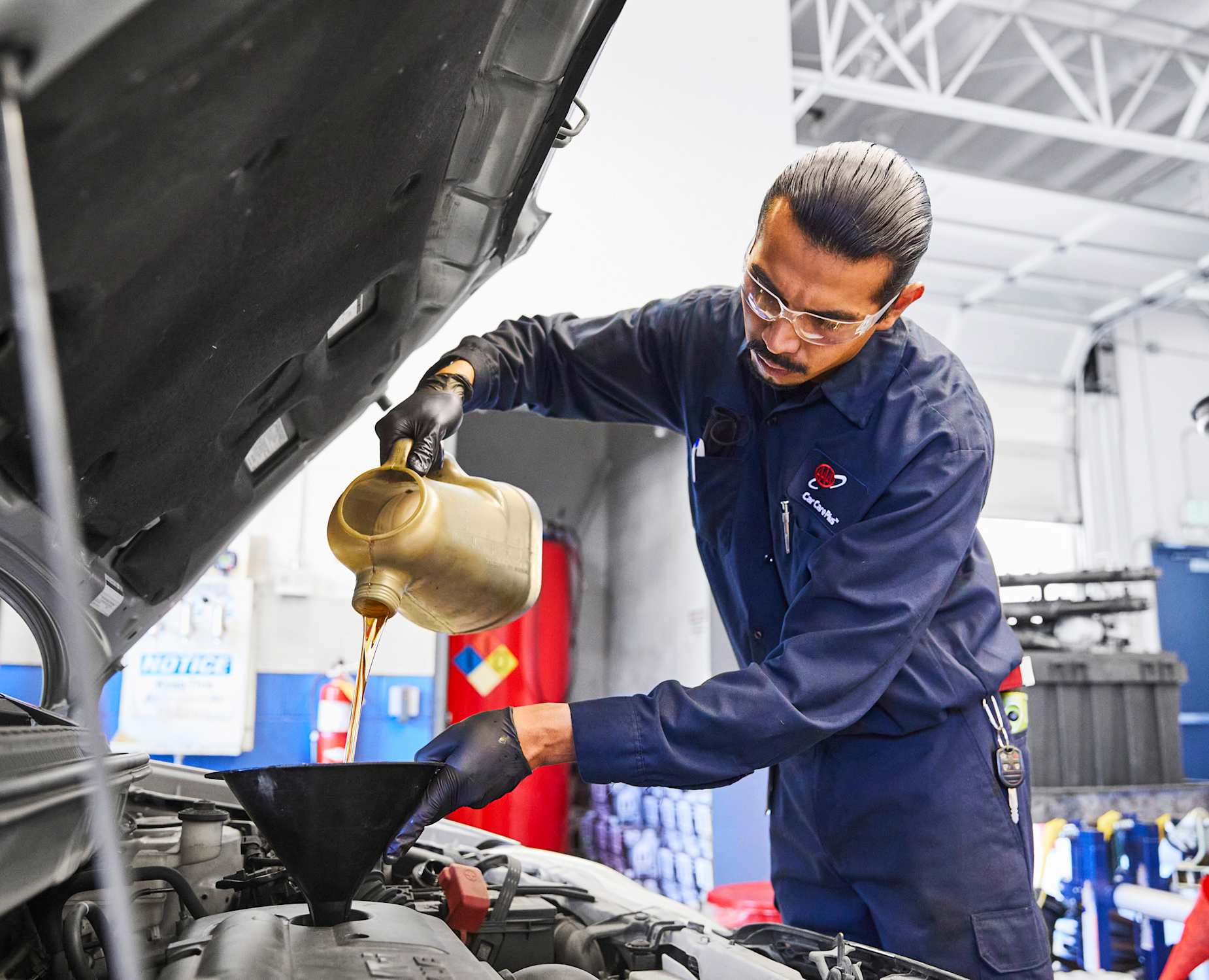 AAA mechanic working on a car with the hood open at an auto repair shop