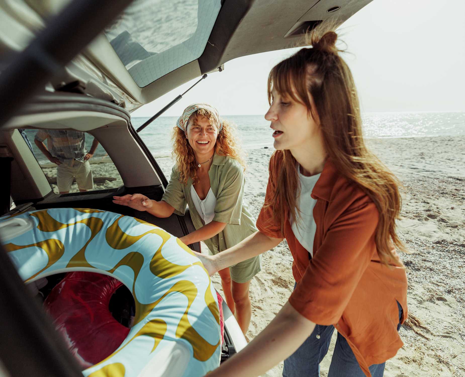 Women putting inflatables into car at beach