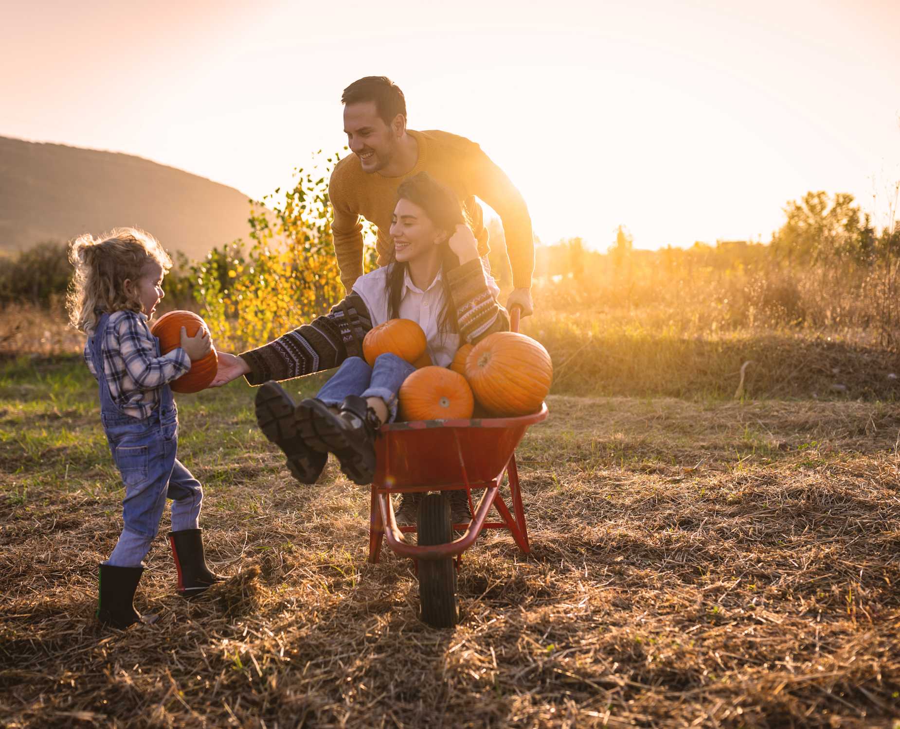 Woman and man in pumpkin patch with their kid