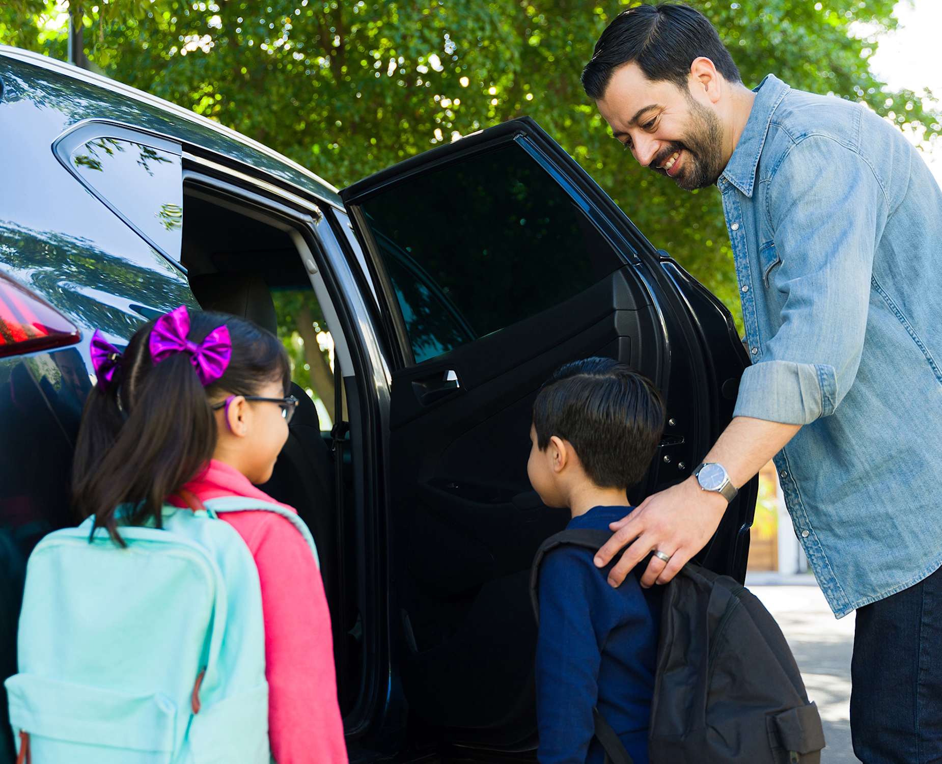 Man helping kids get into car