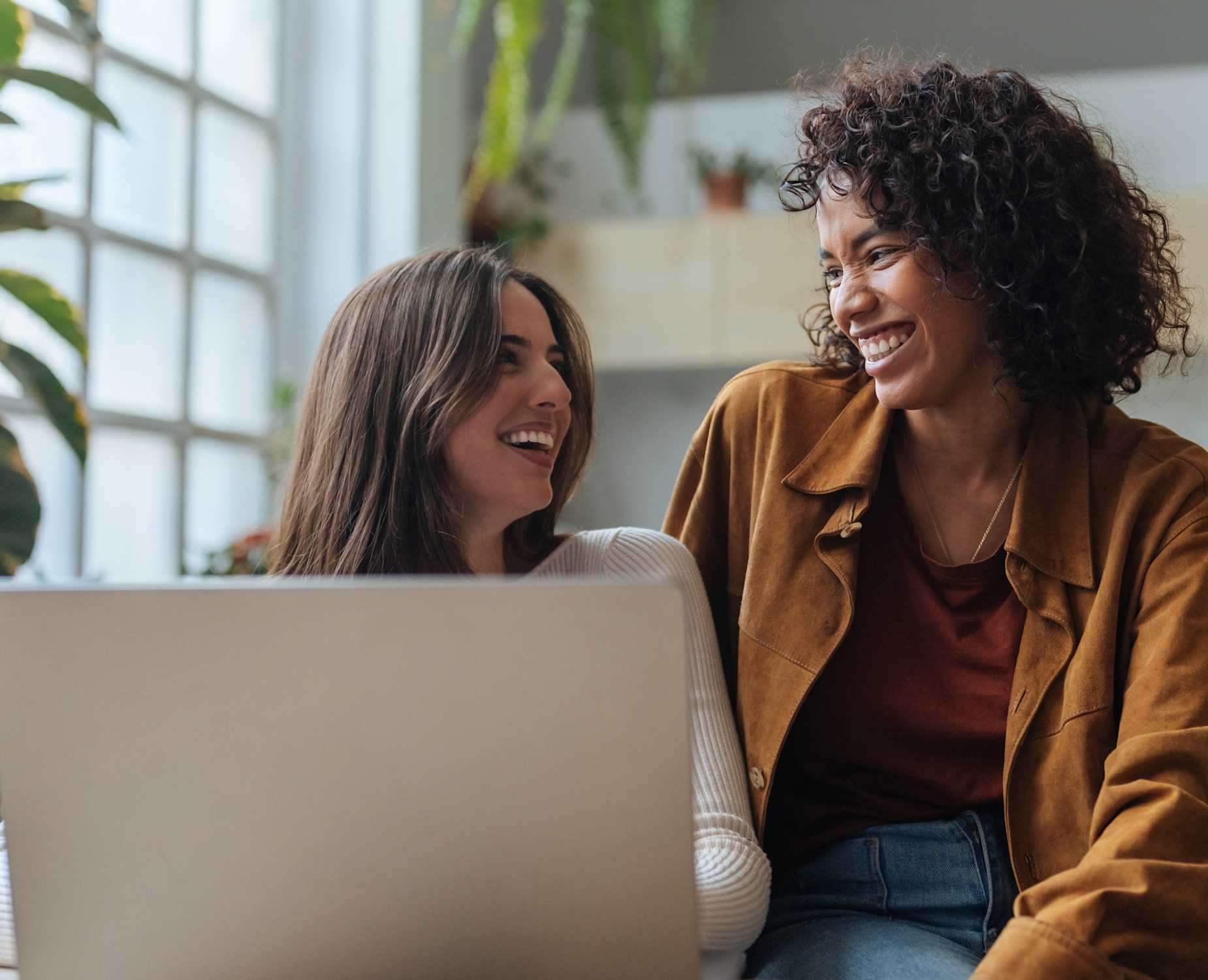 two people sit next to each other at a laptop smiling while reviewing their Bread Savings high-yield savings account