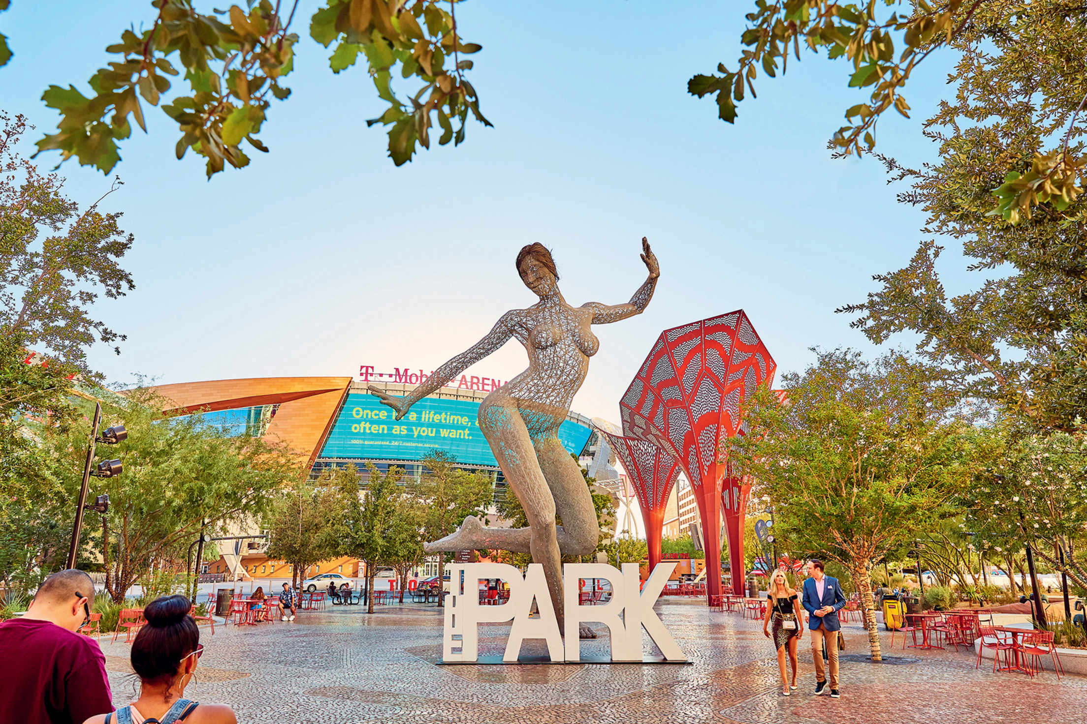 Visitors walk through the Park in Las Vegas outside of T-Mobile Arena near the dancing woman metal statue, image