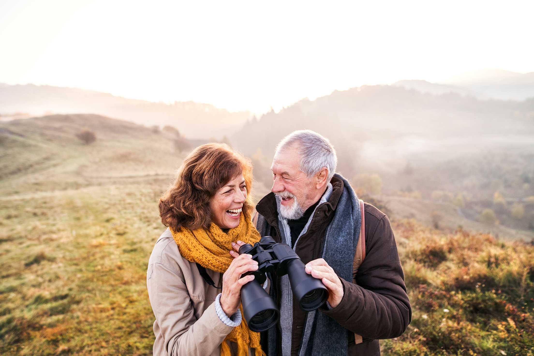 Senior couple look for birds through binoculars on a golden fall hike, picture