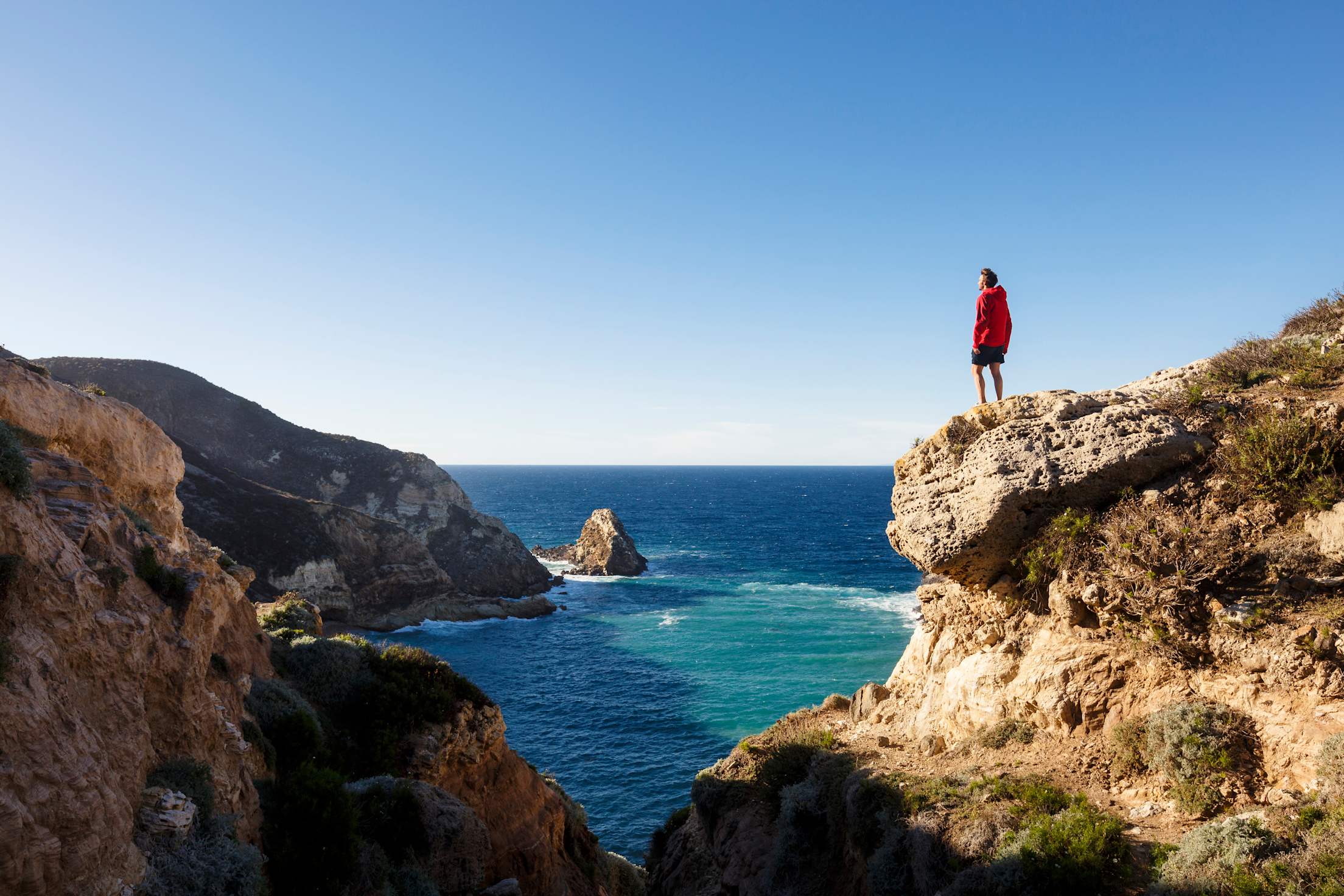 a person stands on rocks overlooking the water at Channel Islands, picture
