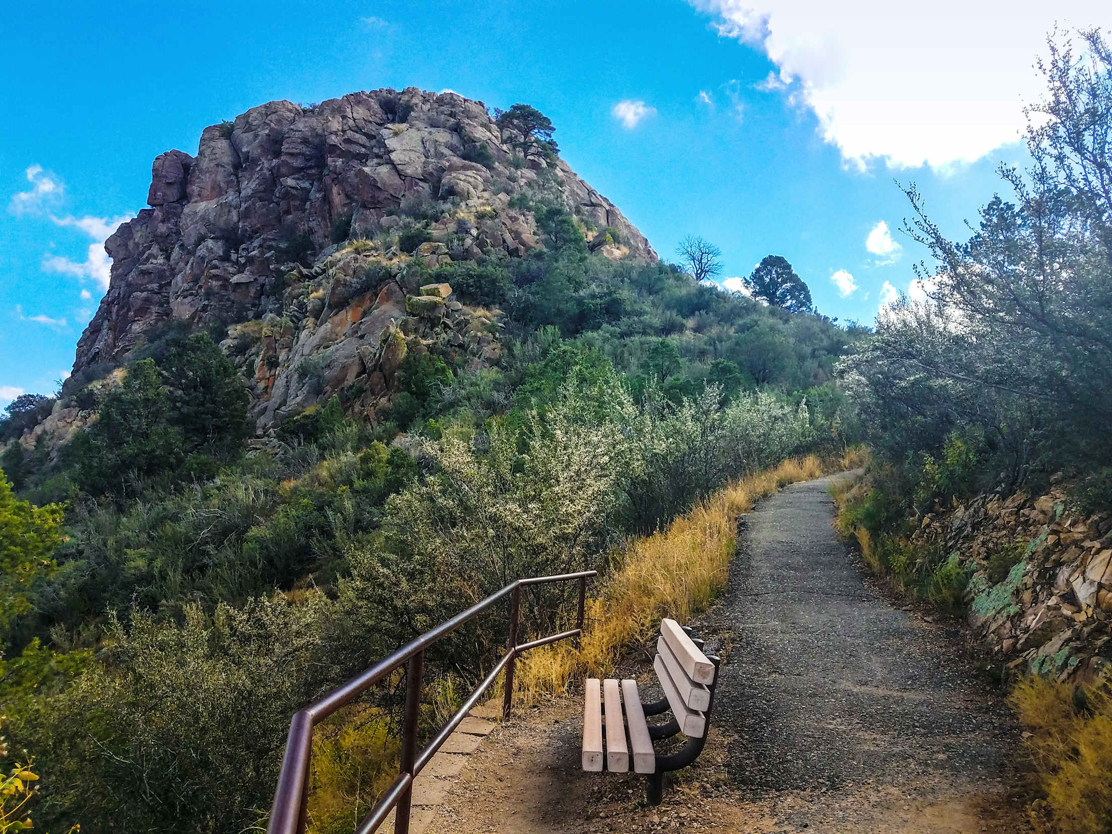 Photo of a bench next to a hiking trail on a mountain
