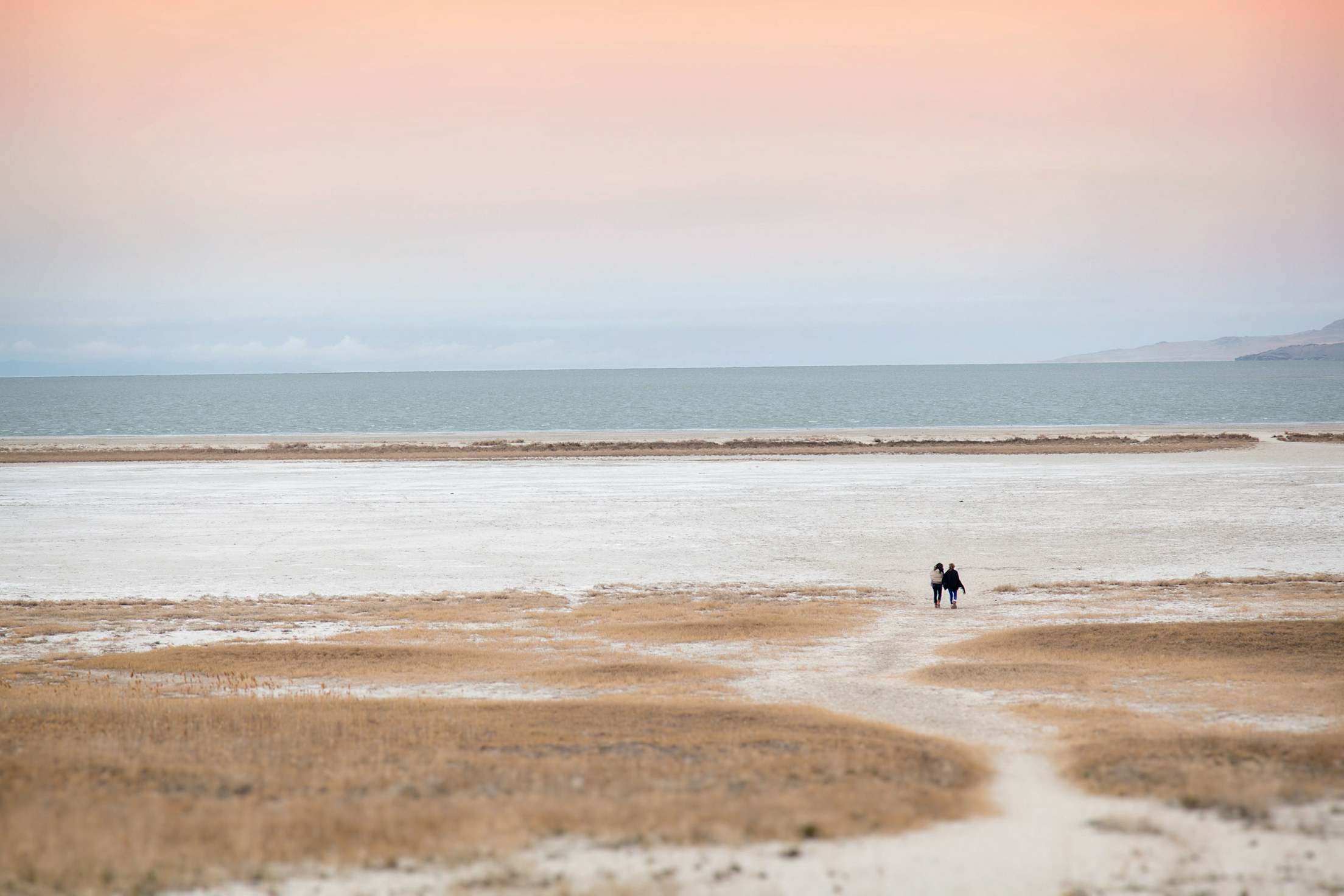 two people walk on Antelope Island’s Bridger Bay Beach at Sunset in Salt Lake City near Great Salt Lake, picture