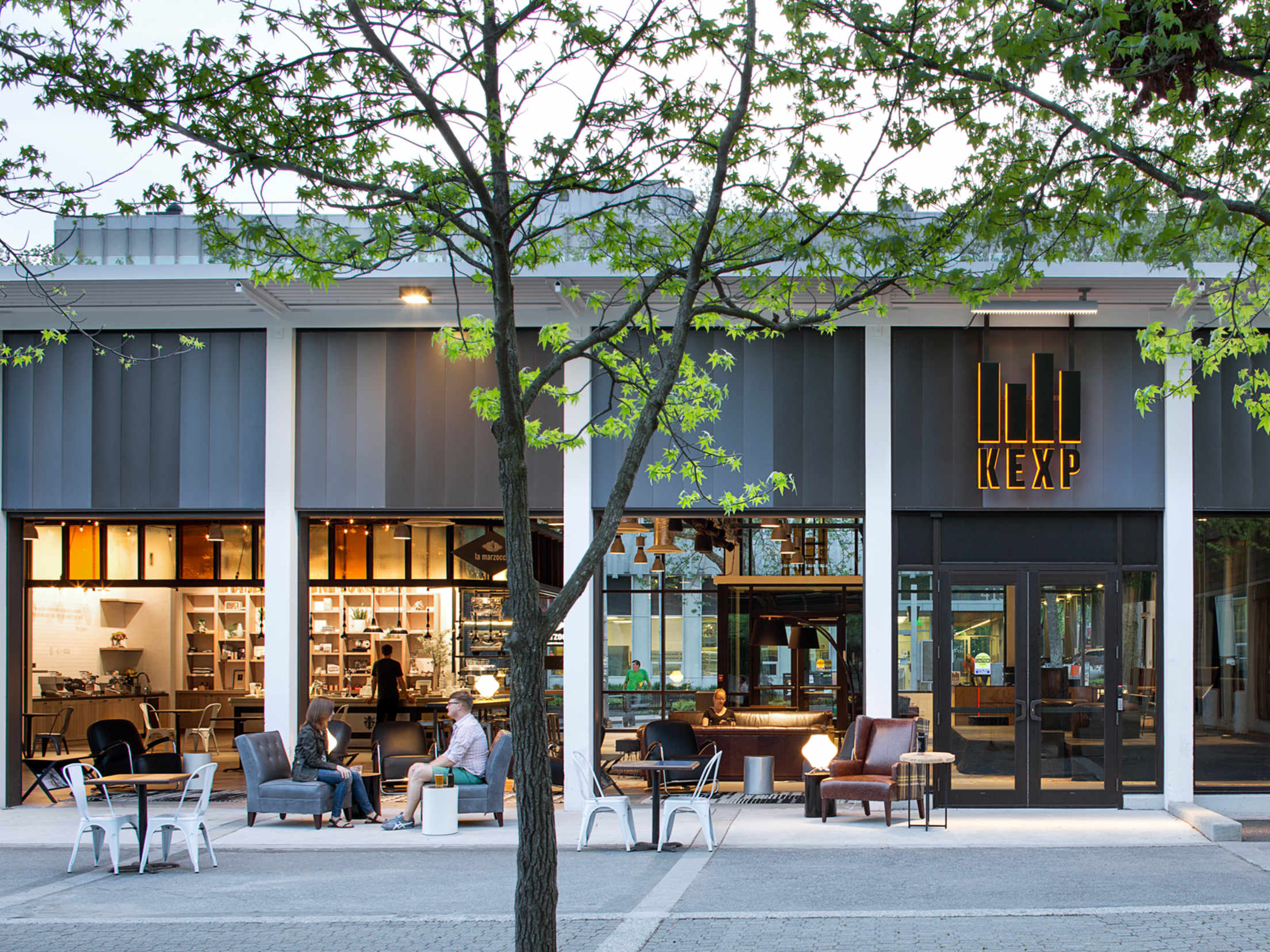 People sit outside of La Marzocco Café and the KEXP gathering space in downtown Seattle near the Space Needle, picture