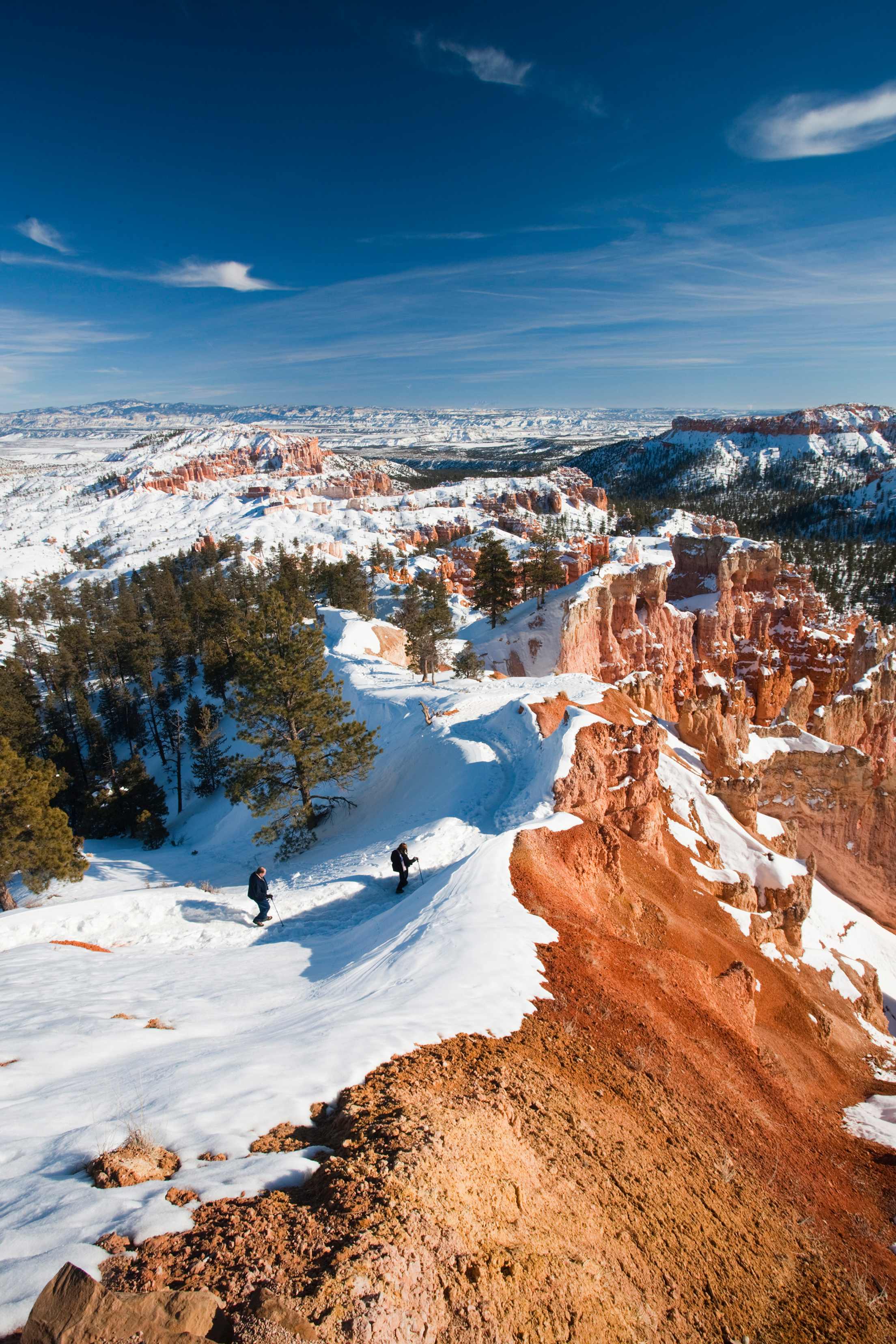 Two snowshoers hike along Bryce Amphitheater in Bryce Canyon's National Park, picture