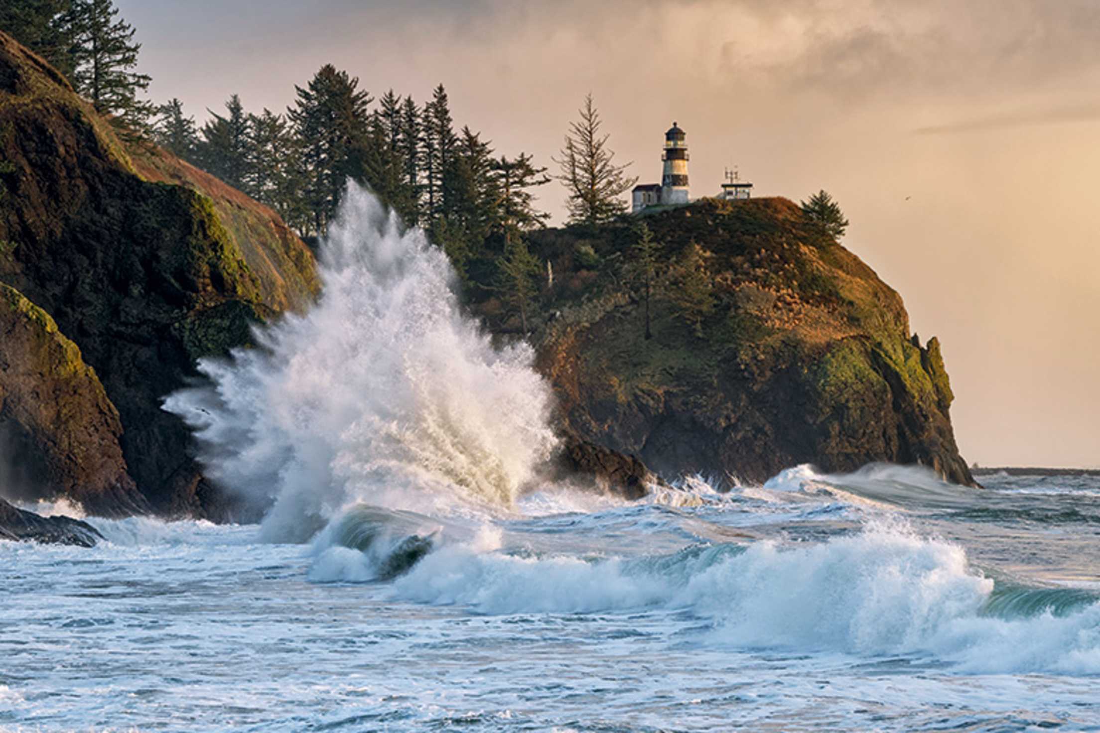 waves crash on the rocky shoreline at Cape Disappointment Lighthouse in Washington, picture
