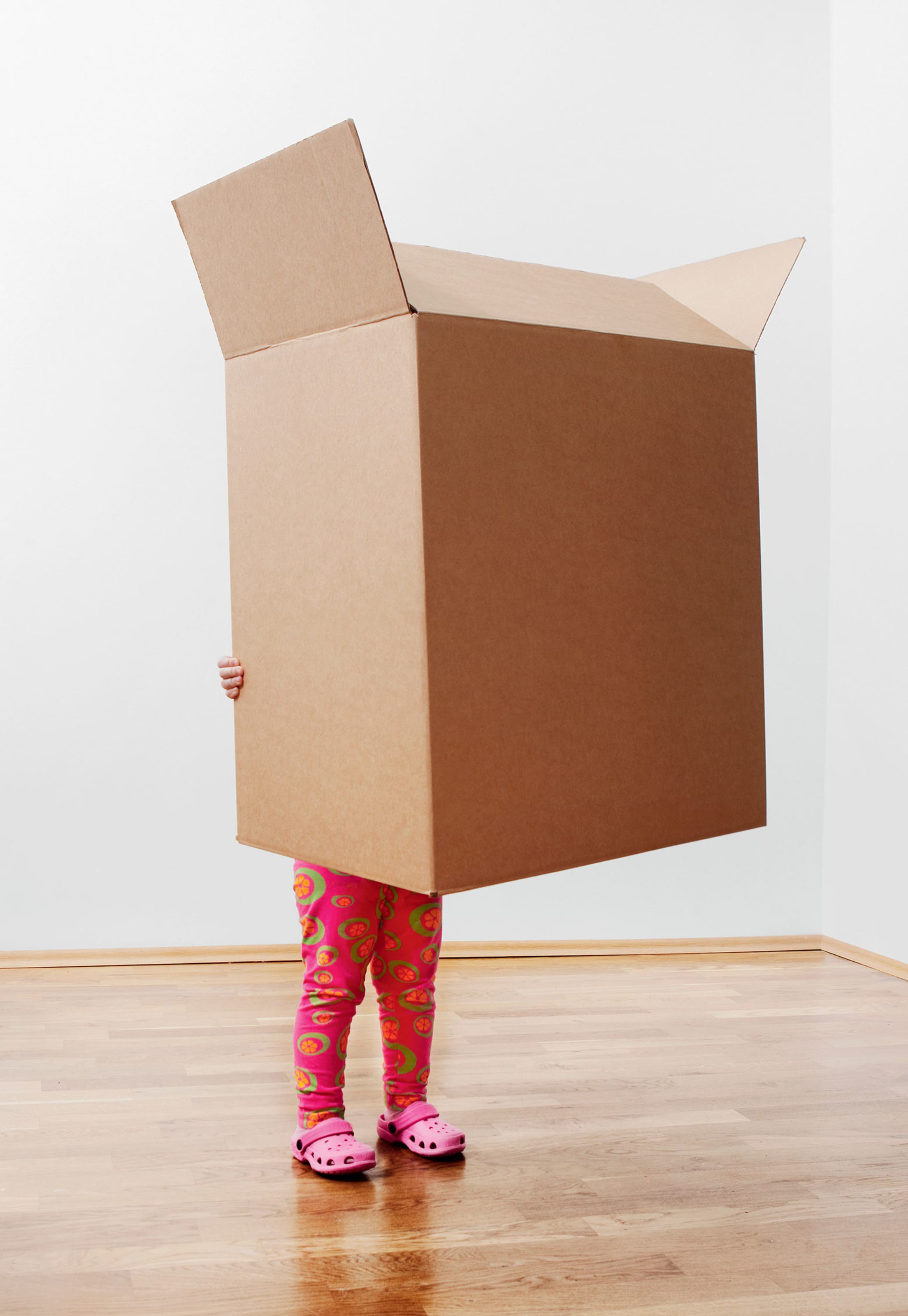 child holds—and, except for legs, is obscured by—large cardboard box, picture