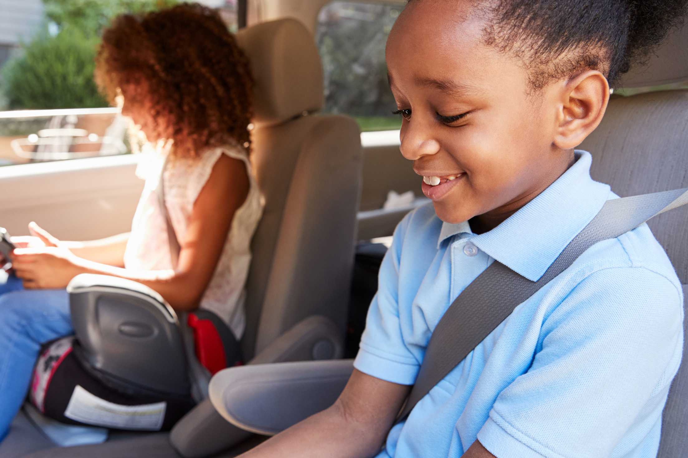 two girls in AAA inspected booster seats in the middle seat of an SUV or van