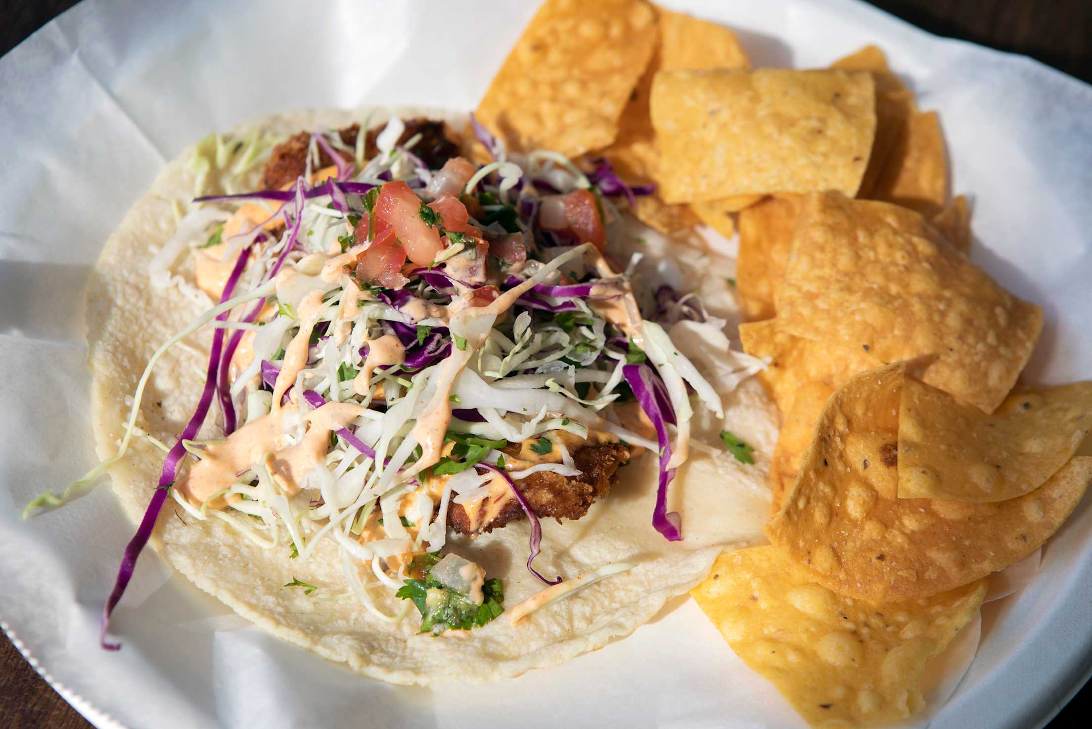 fish tacos topped with shredded red cabbage, cilantro and tortilla chips on the side at La Sirena Grill in Laguna Beach, California
