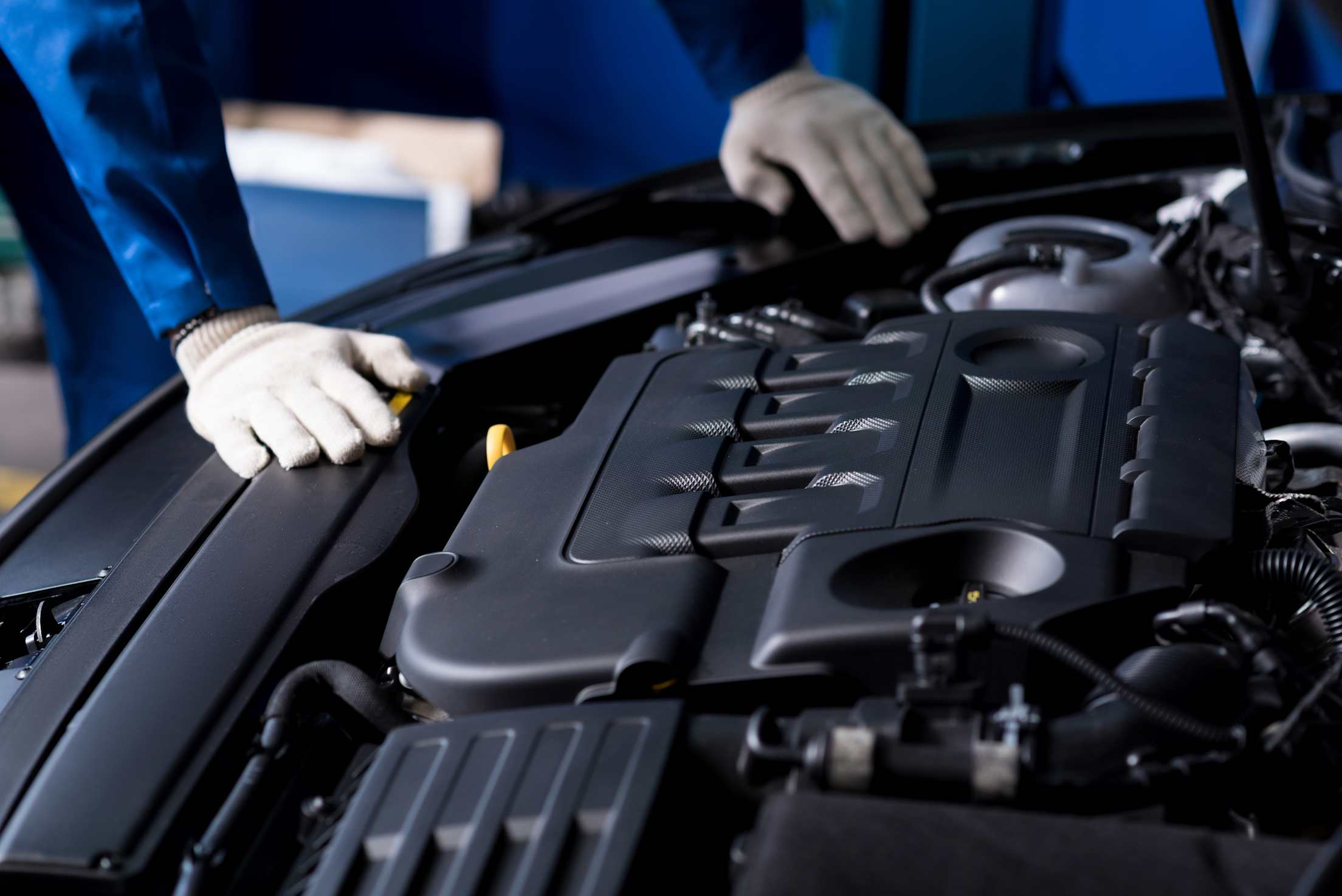 mechanic's gloved hands on a car engine