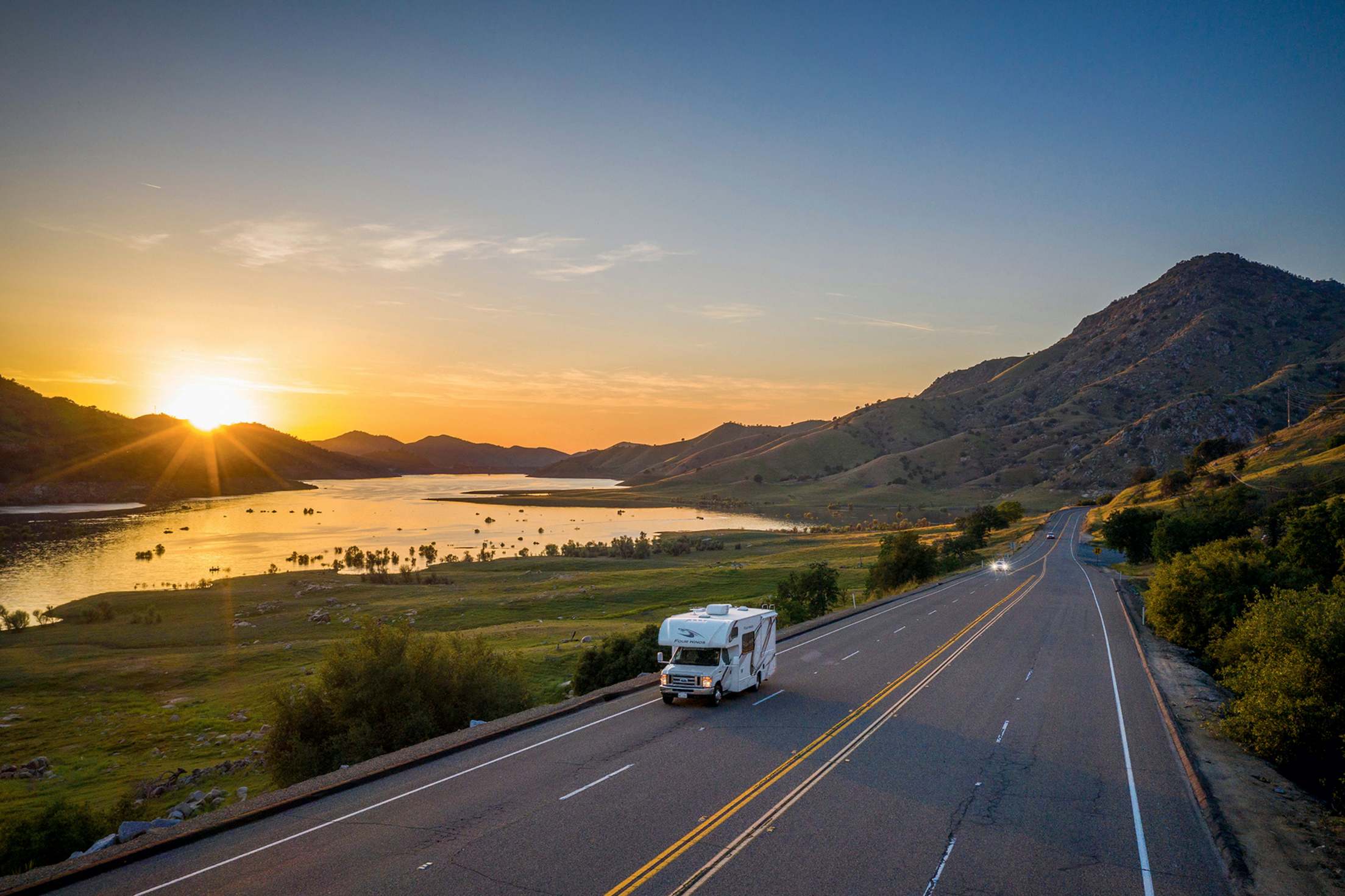 An RV on the highway at sunset.
