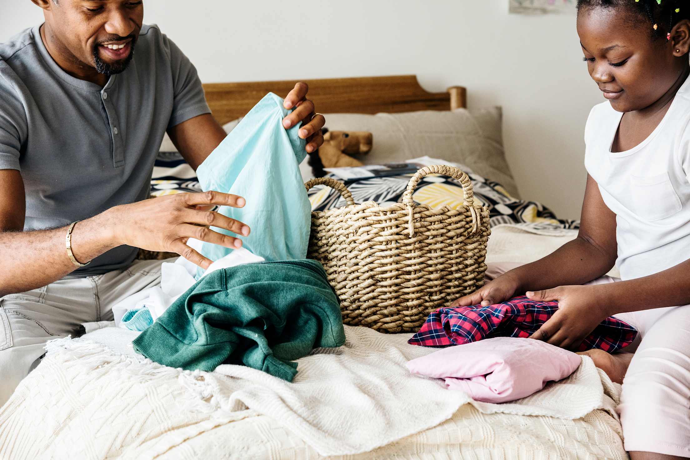 A father and daughter fold clean laundry together.
