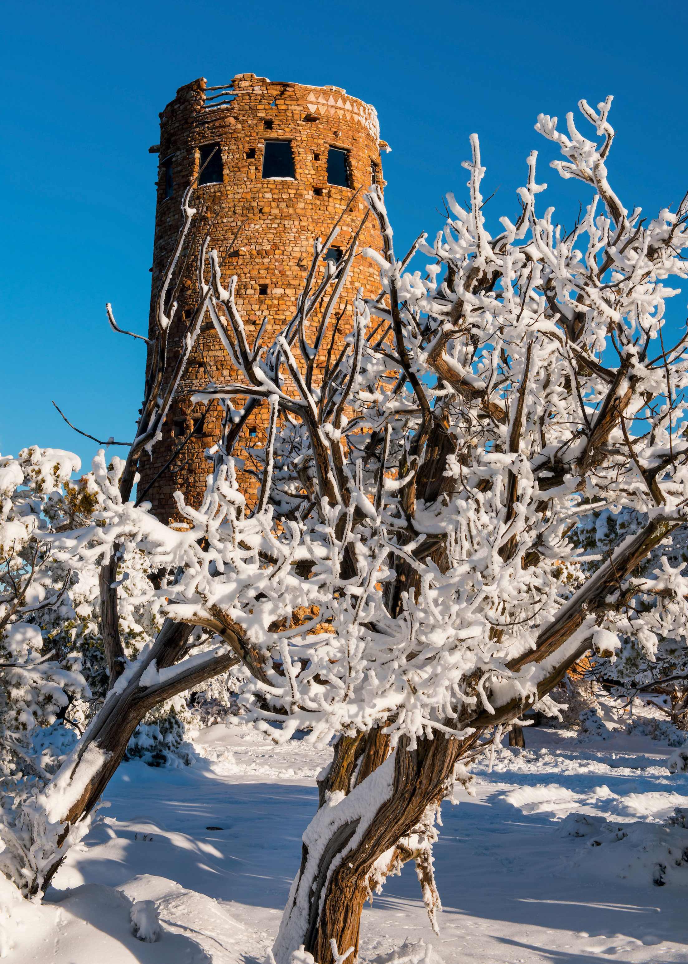 Desert View Watchtower stands sentry over a snowy scene on a cold, clear day at the South Rim of Grand Canyon National Park, Arizona