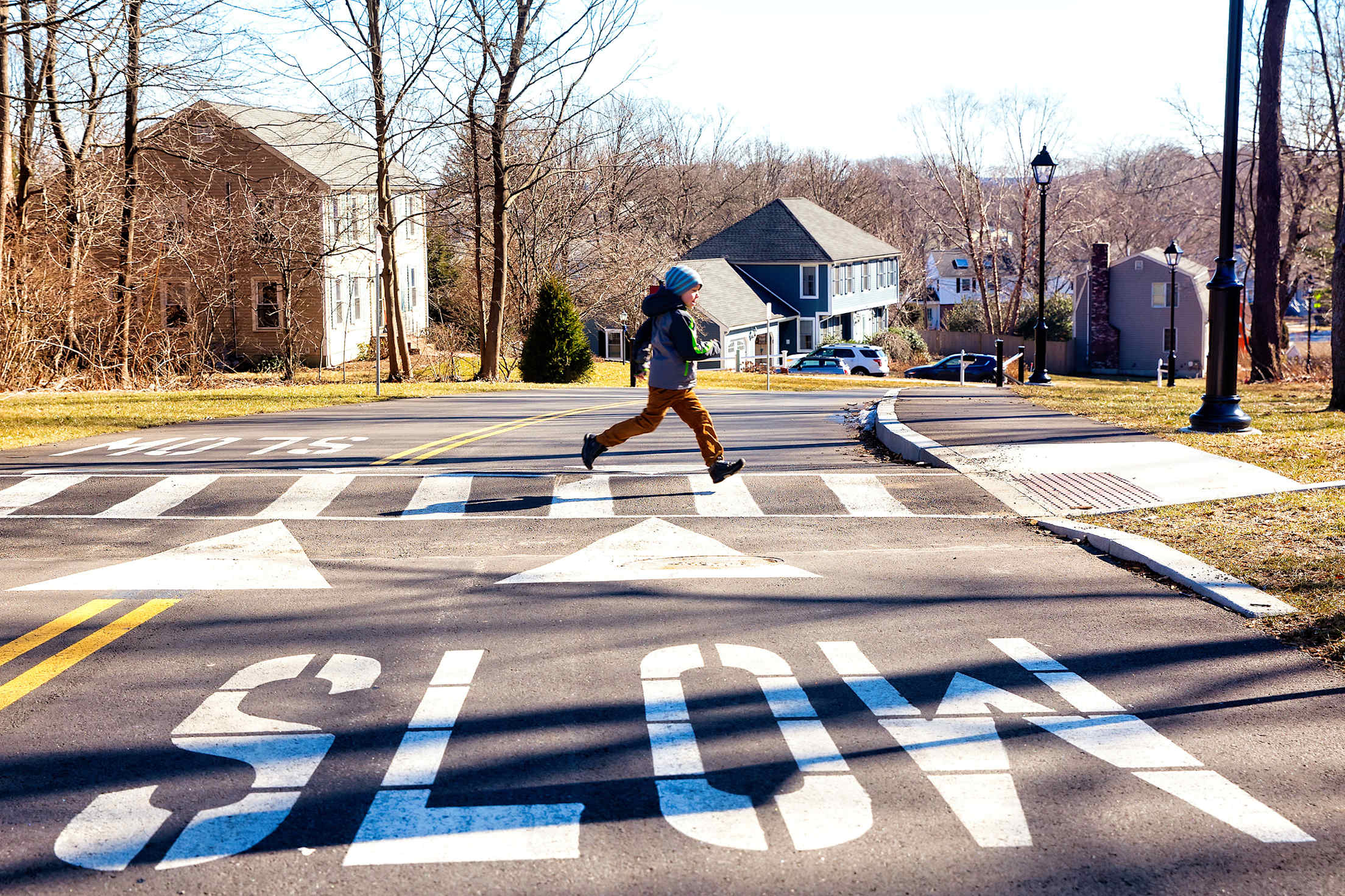 A young boy runs across a crosswalk.