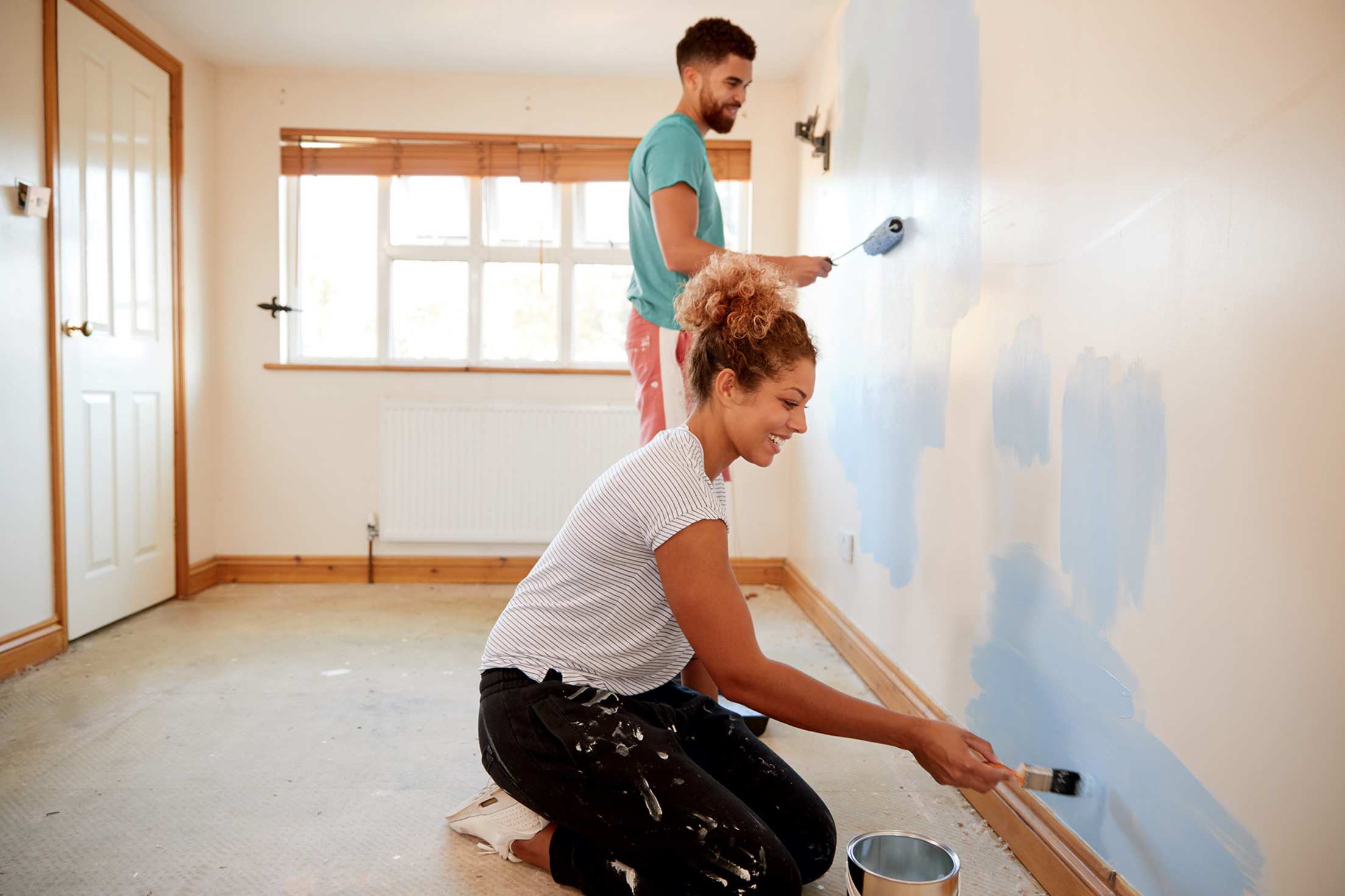 A couple paint a bedroom together.