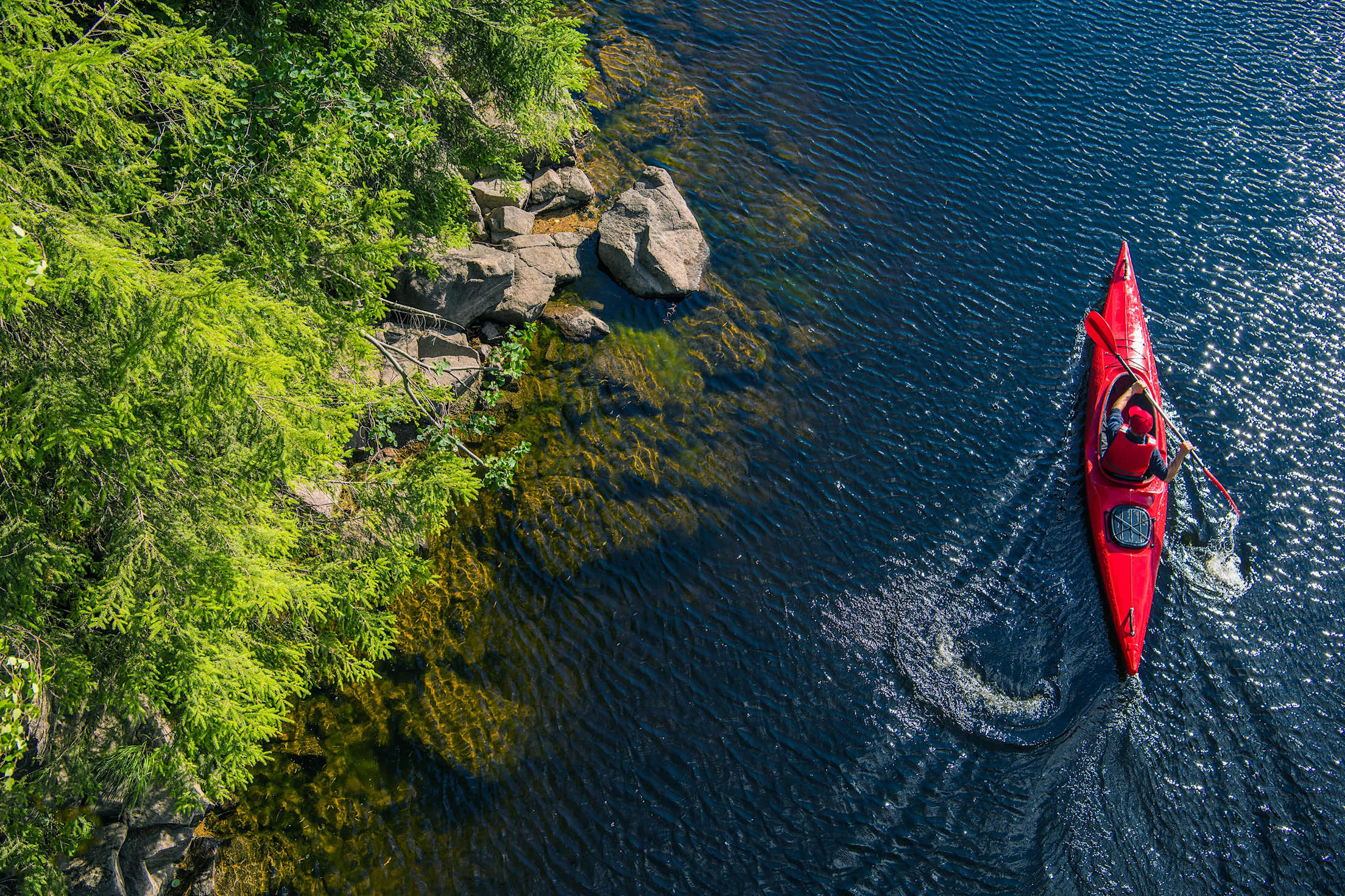 A kayaker paddles along the shoreline.