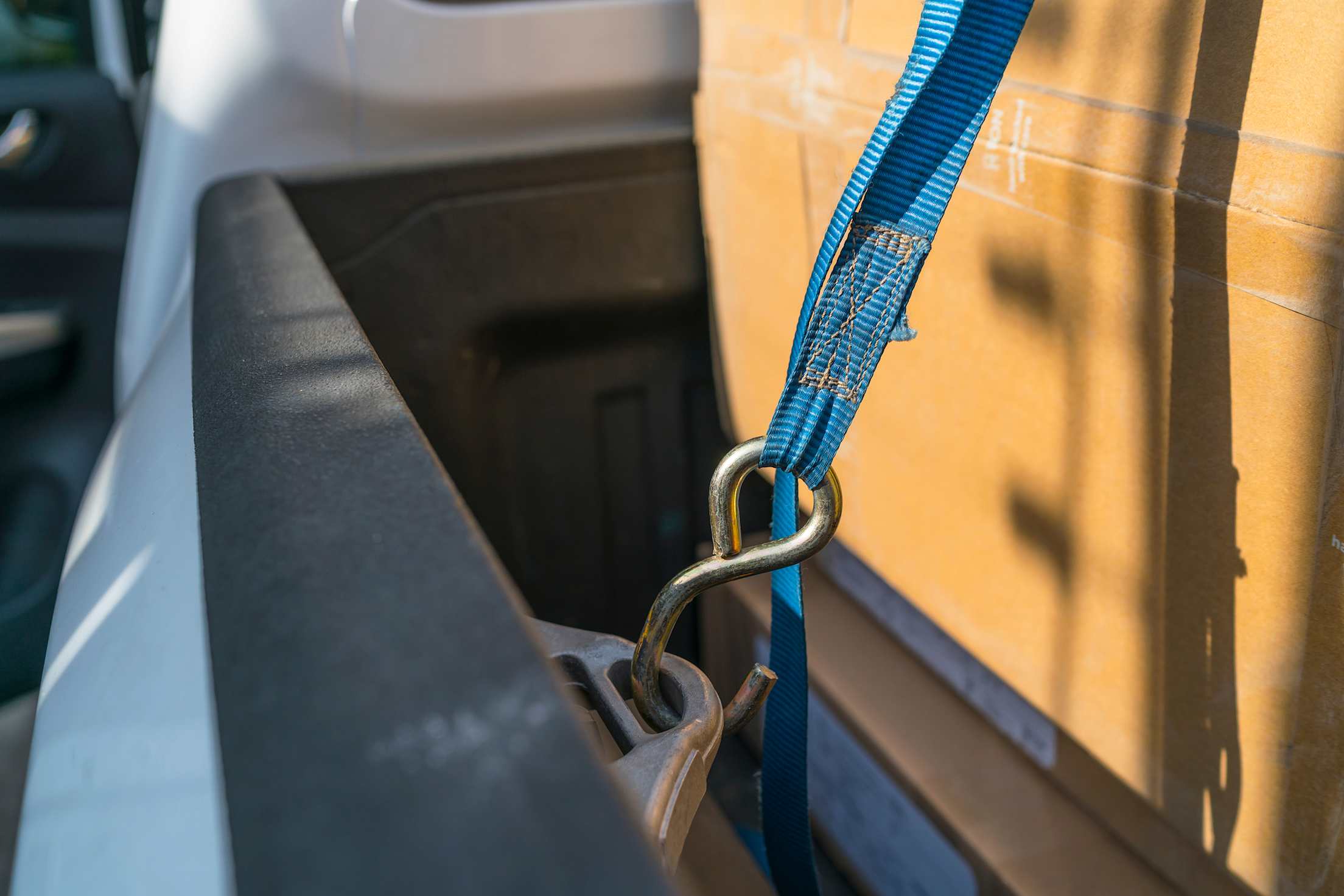 A cargo strap holds down boxes in the back of a truck.