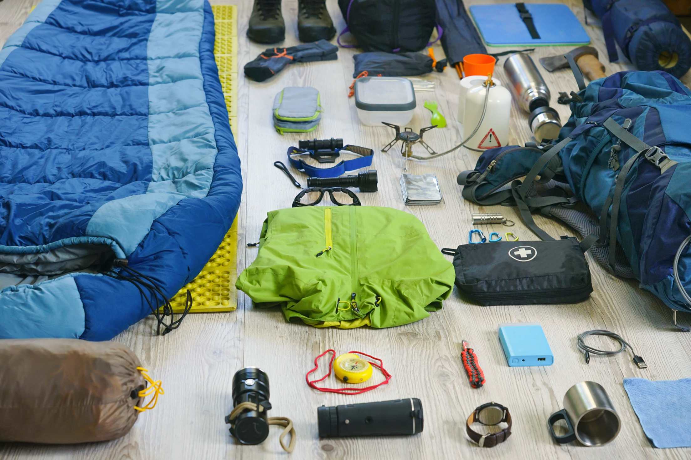 Camping gear layed out on a hardwood floor.