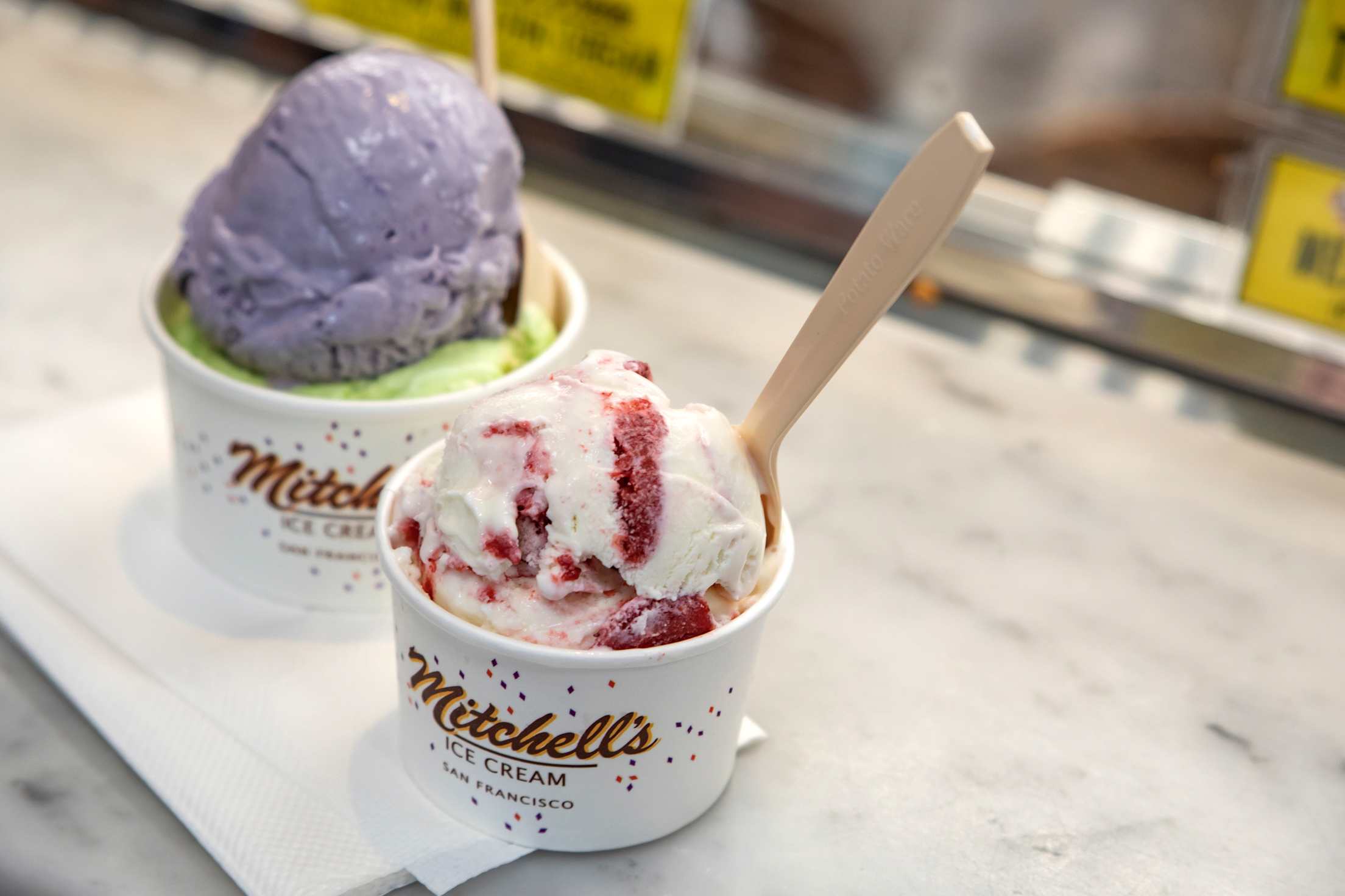 Two cups of Mitchell's Ice Cream on the ice cream shop's counter.