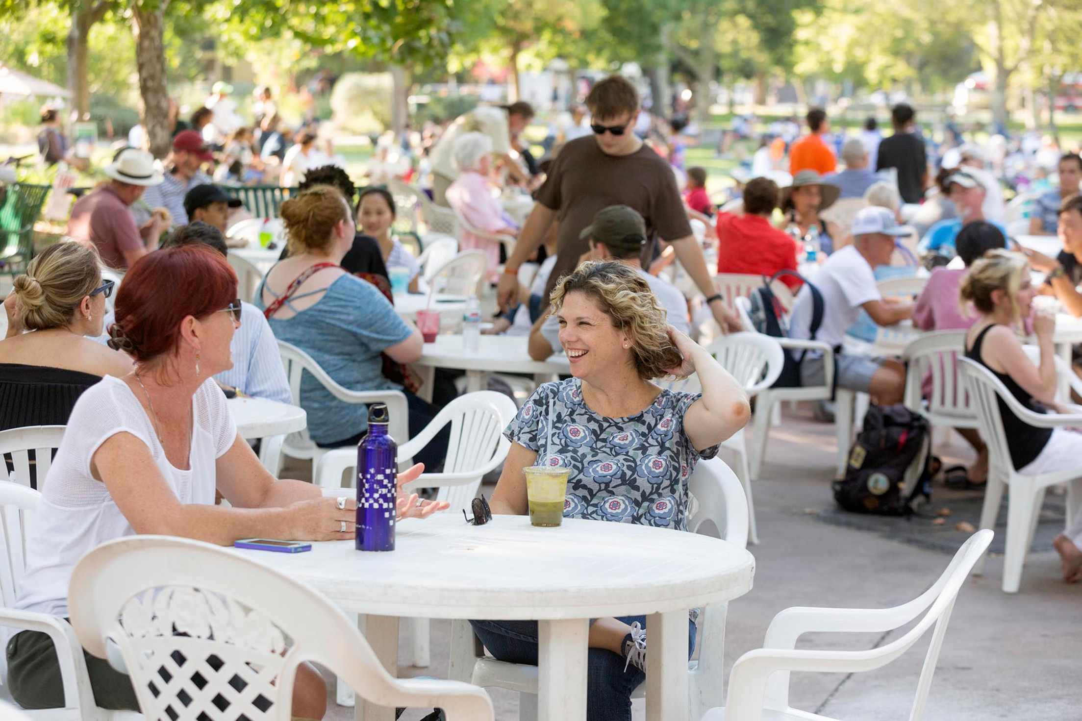 People sit at tables during Picnic in the Park in Davis, California, image