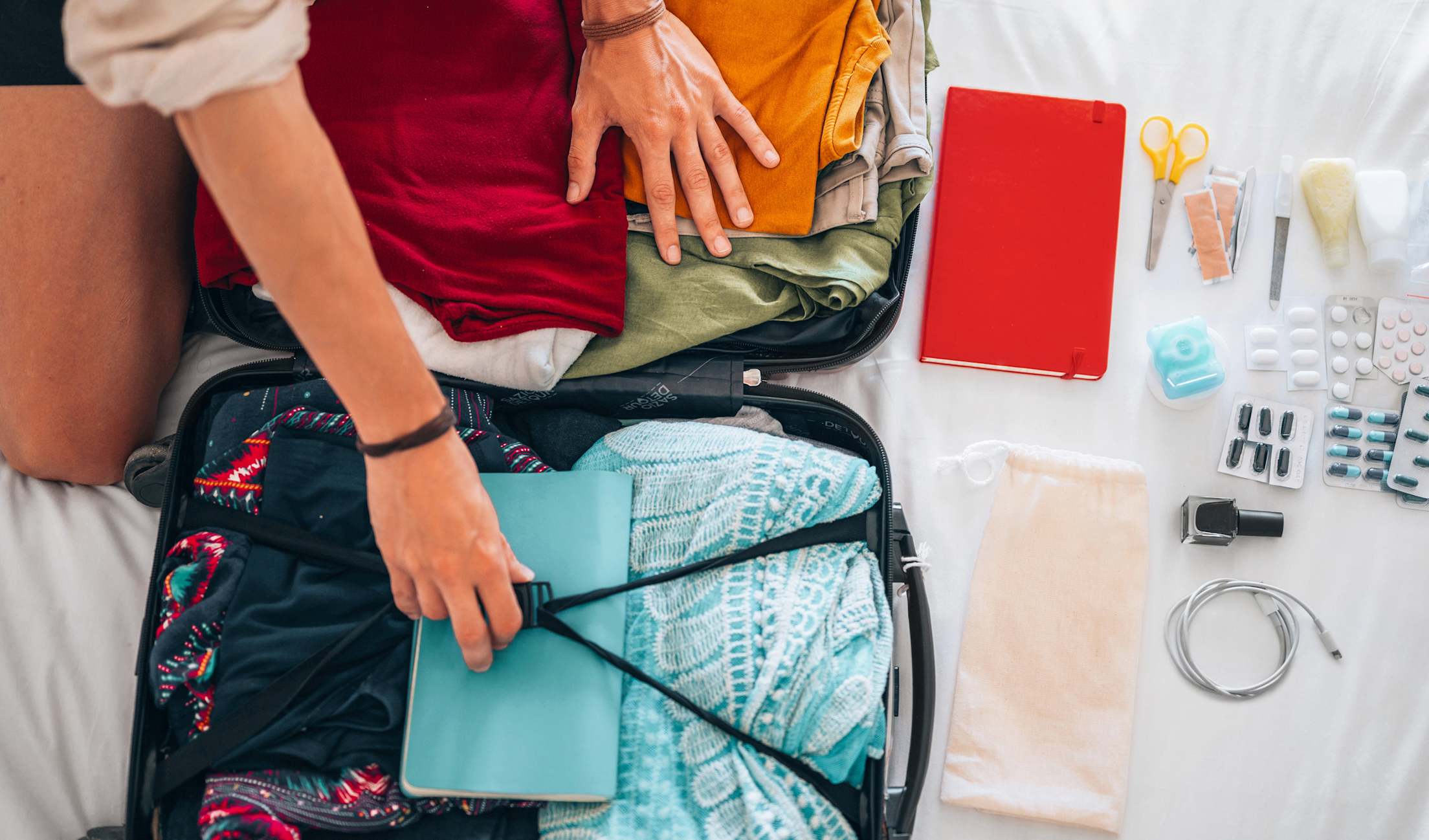 A traveler packs a suitcase with clothes and medications for an international trip.