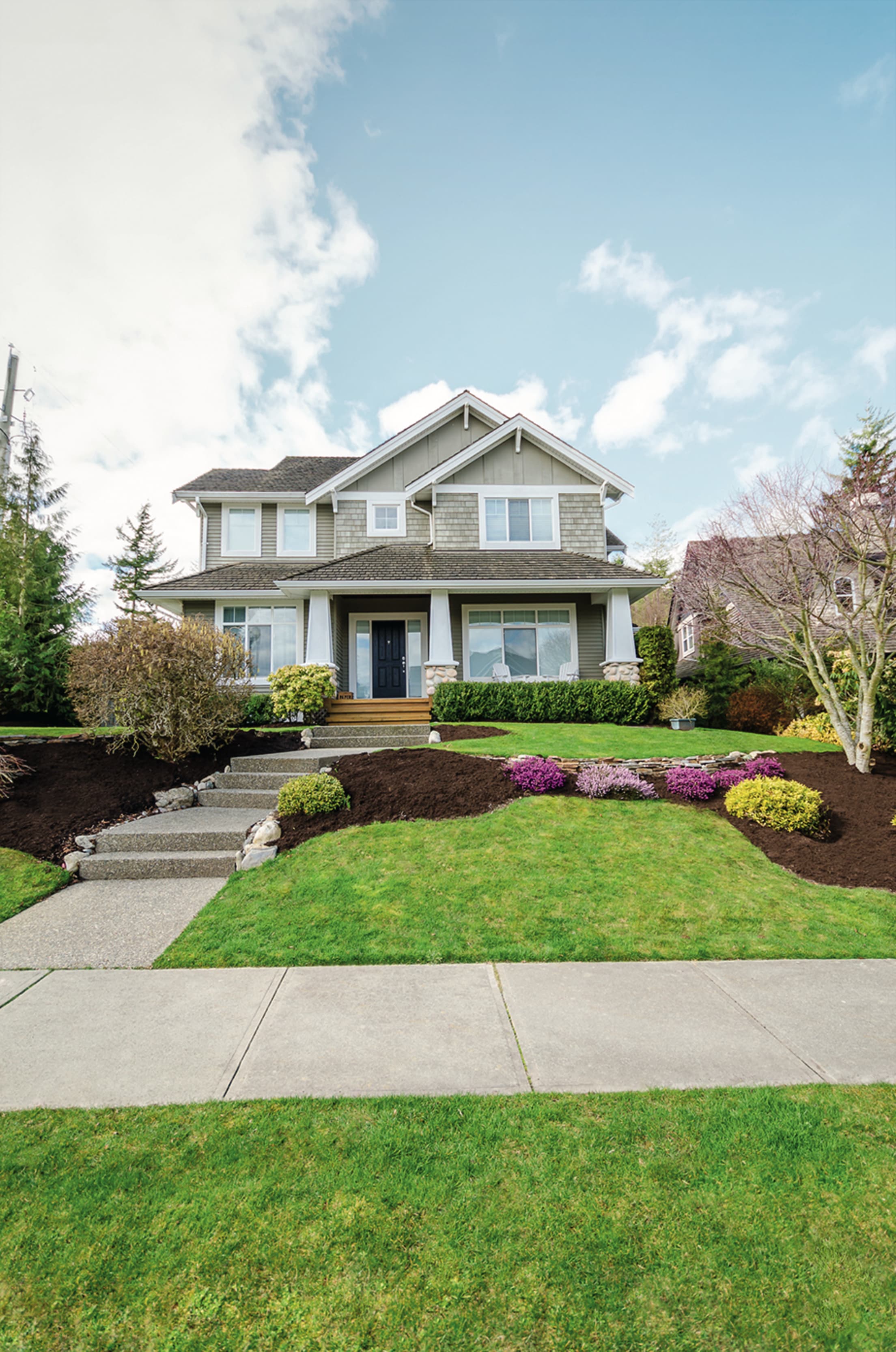 front exterior of two-story home with maintained lawn in the foreground and blue sky with white clouds in the background