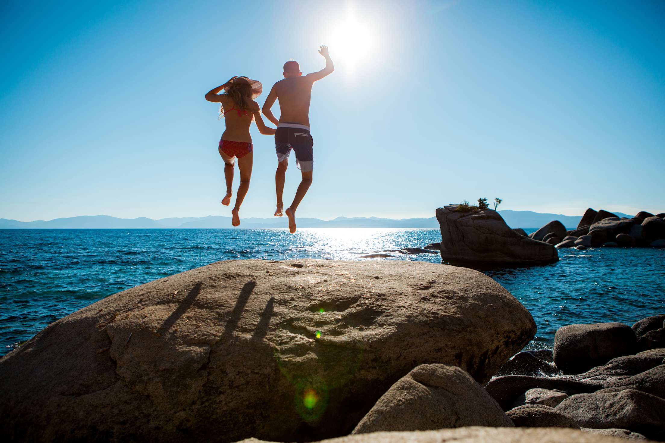 Two people jump into Lake Tahoe near Bonsai Rock.