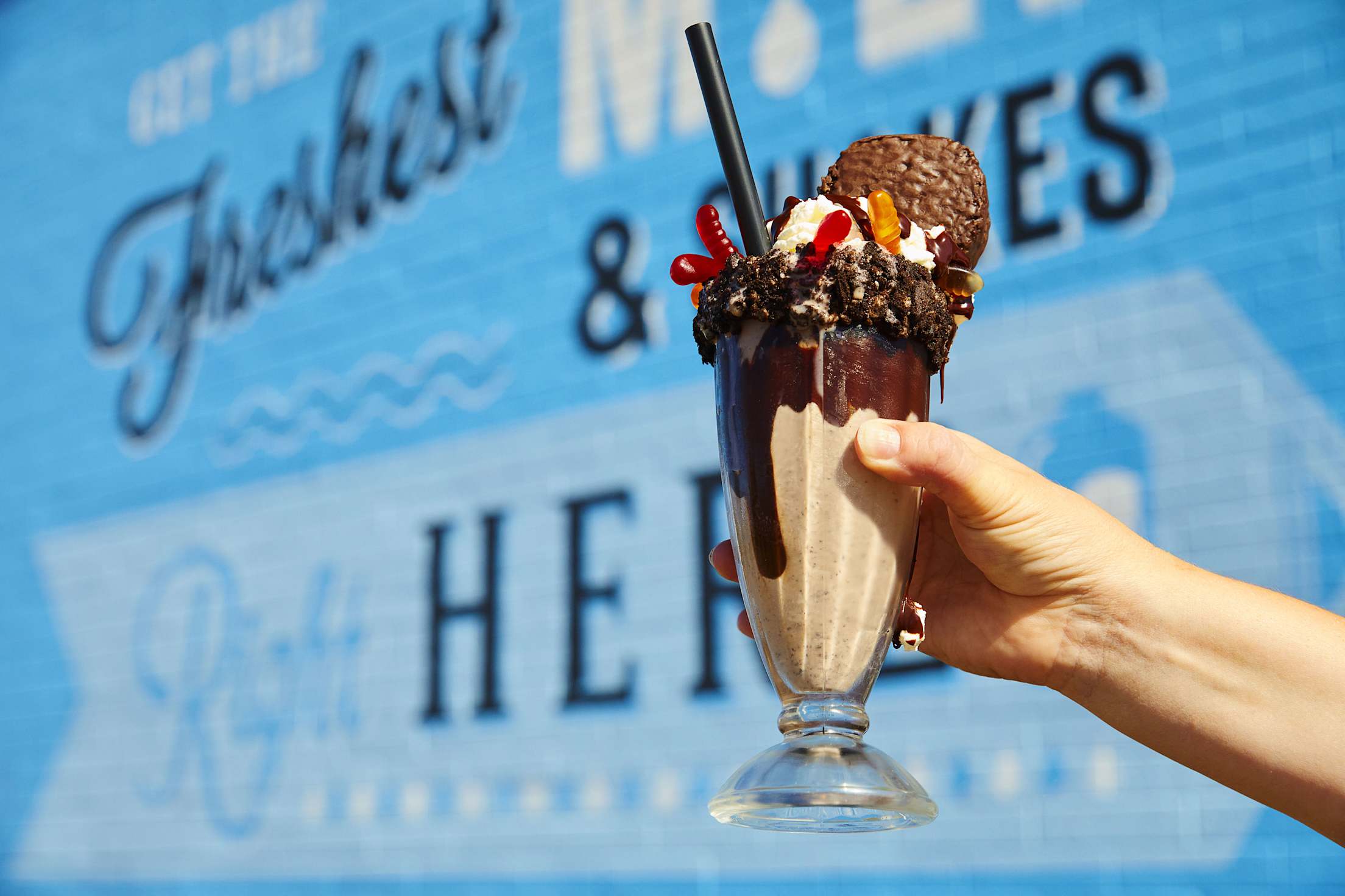 A glass of the The Dirt Stack milkshake, which is a vanilla shake in a chocolate syurp lined glass, topped with oreo crumble, gummy worms and a hostess cupcake, from Danzeisen Dairy Creamery Store.