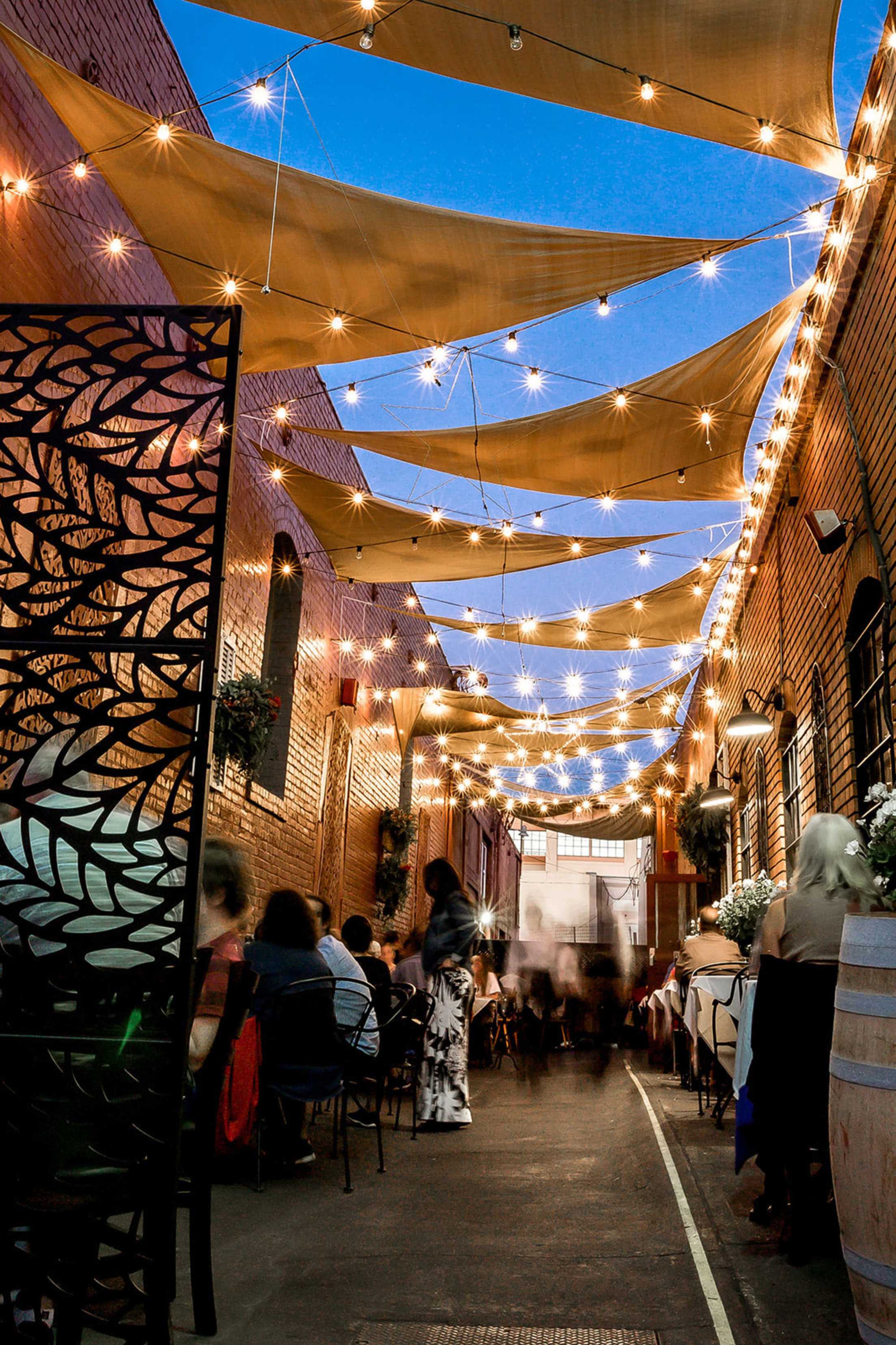 The outside dining space at La Gare French Restaurant is lit with string lights.