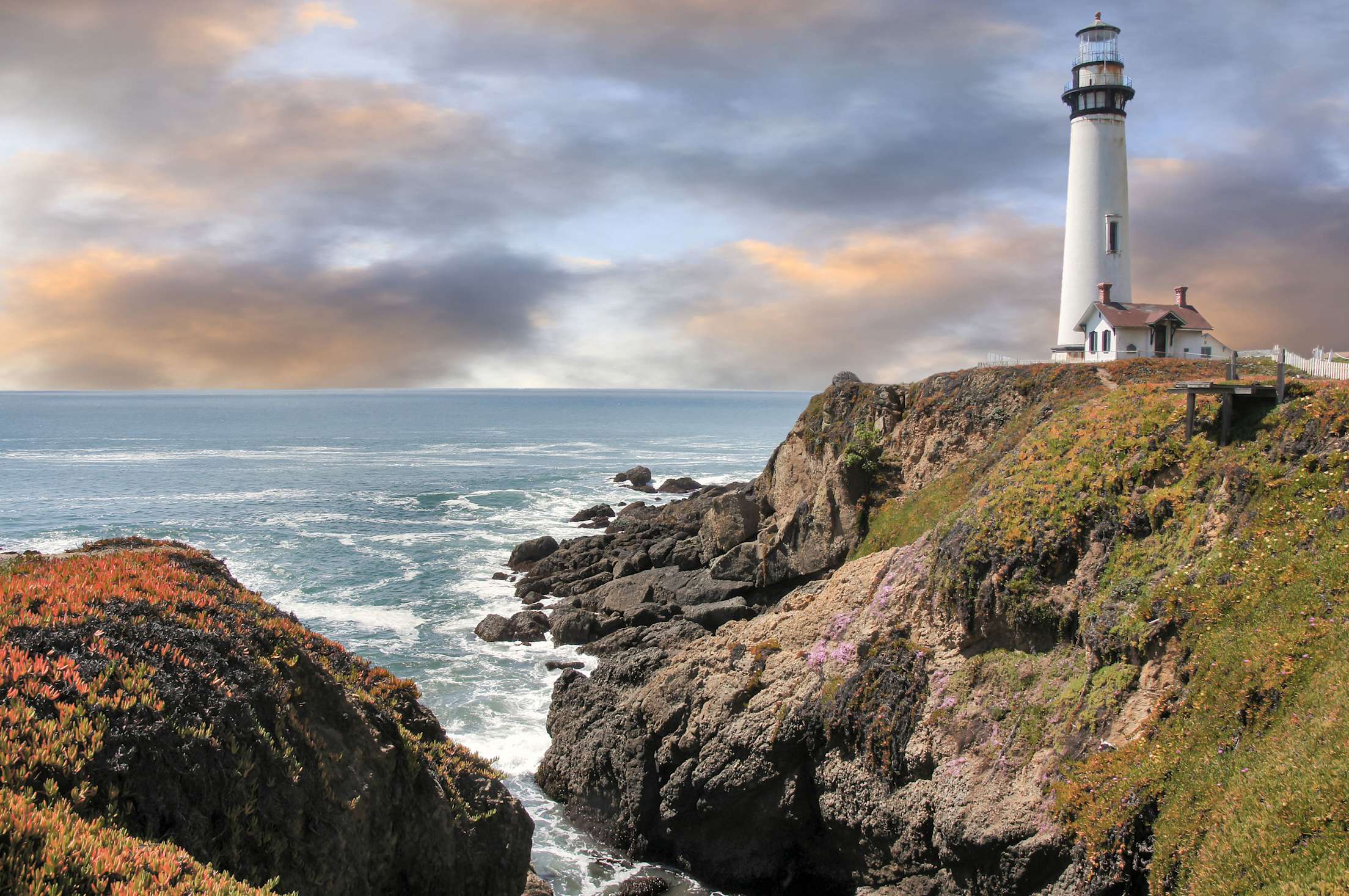 Pigeon Point Light Station perched on the coast on a partly cloudy day.