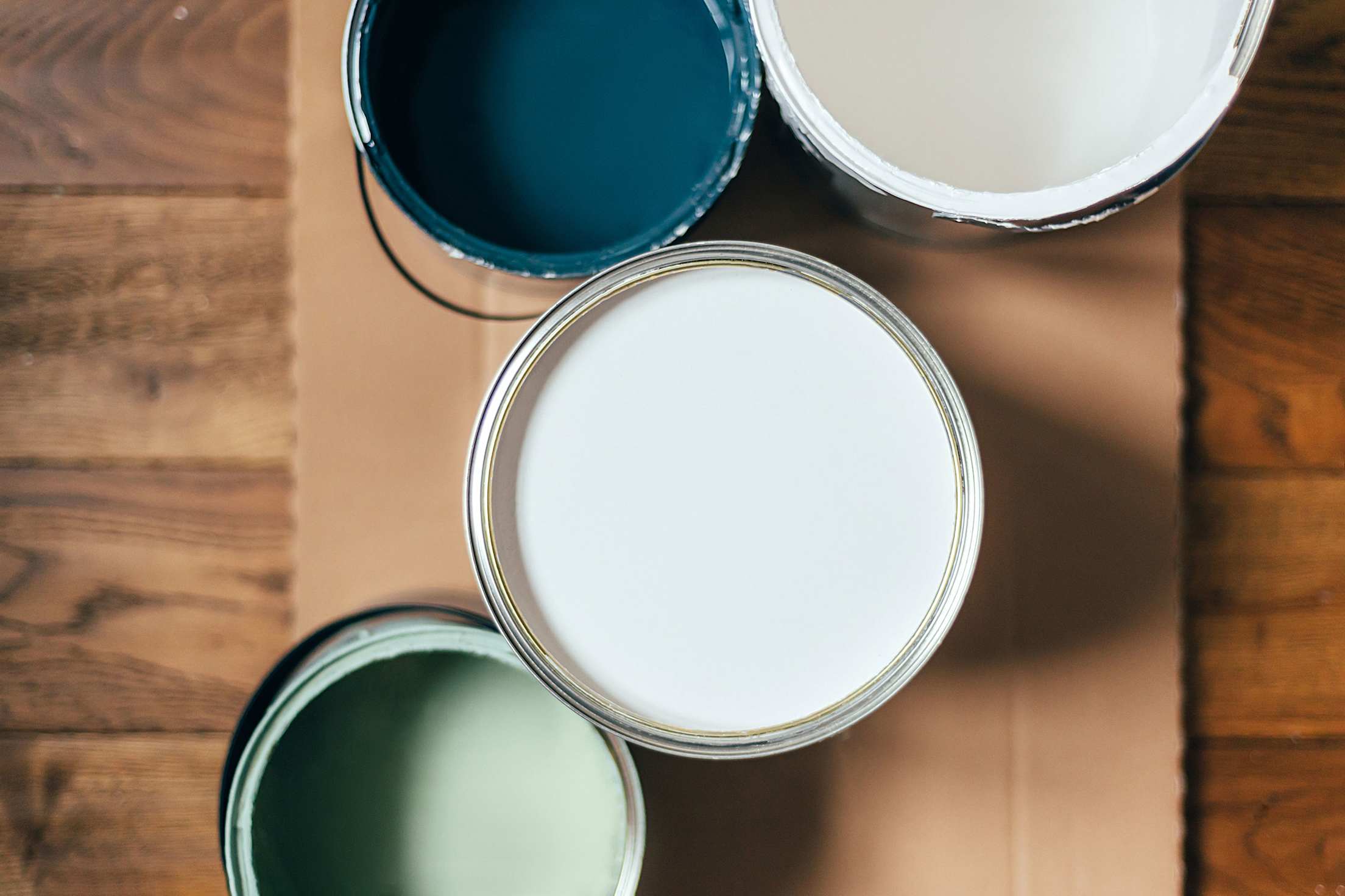 Open cans of blue and white paint on a floor.