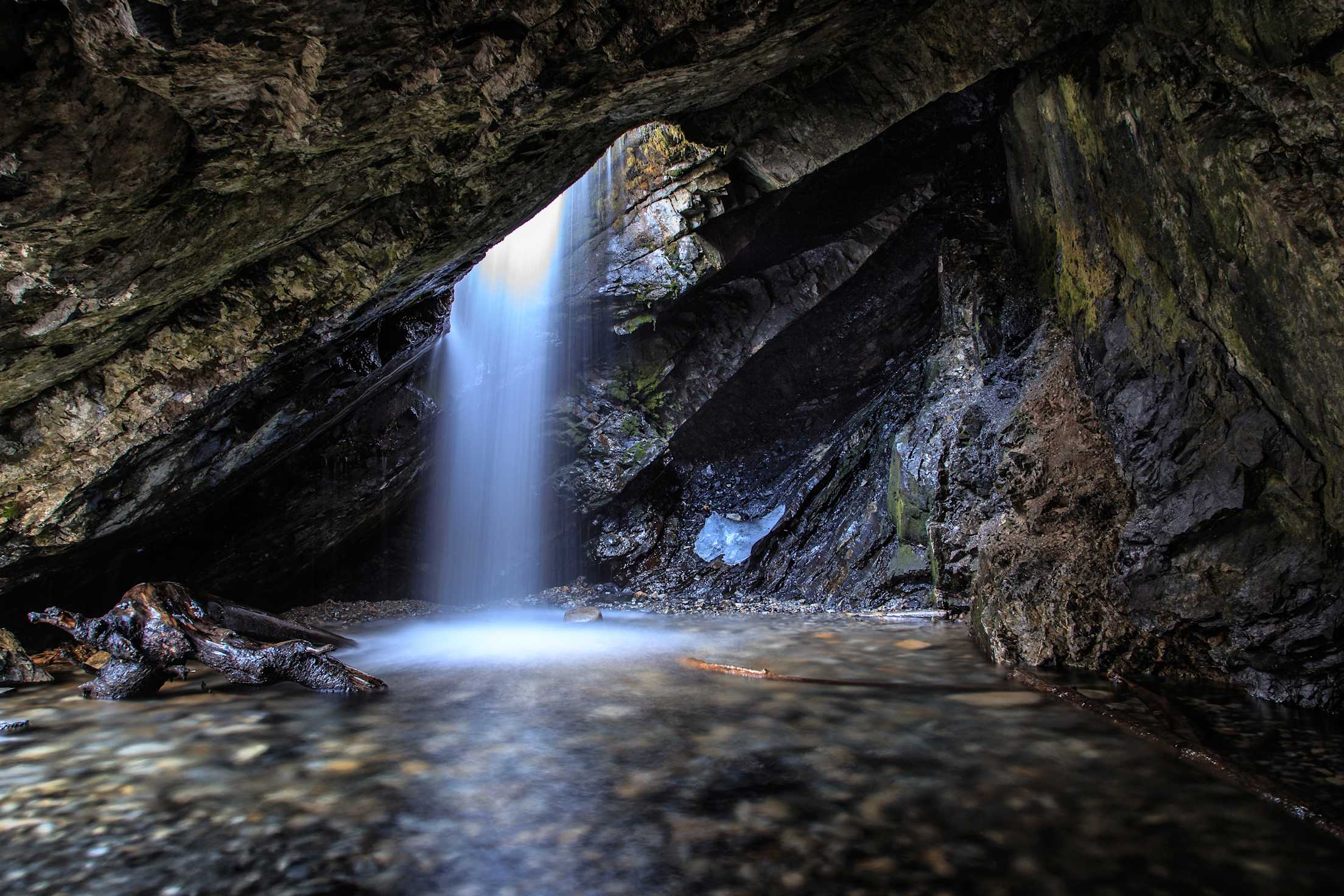 Water falls through a hole in the rock at Donut Falls in Big Cottonwood Canyon, Utah.