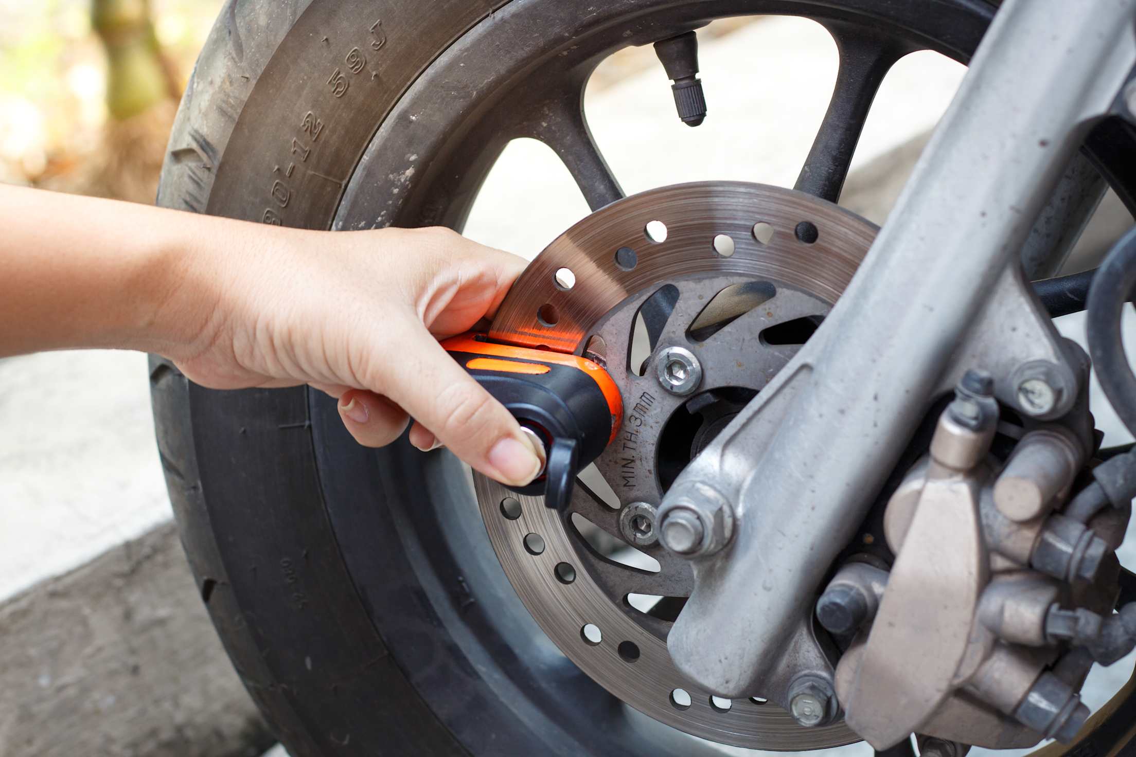 A rider puts a disc brake lock on their motorcycle.