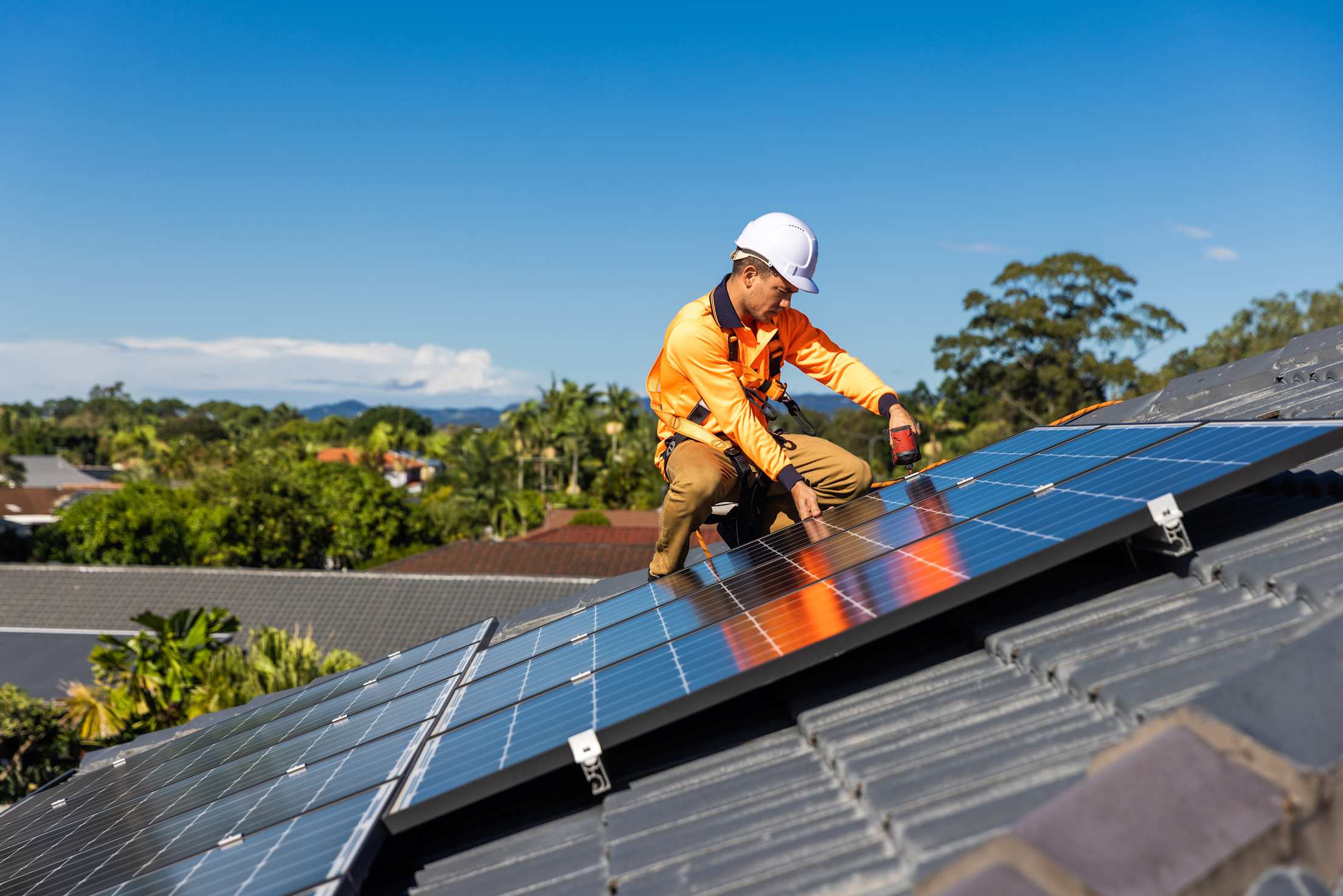 A solar installer screws a panel into the supports on a home's roof.